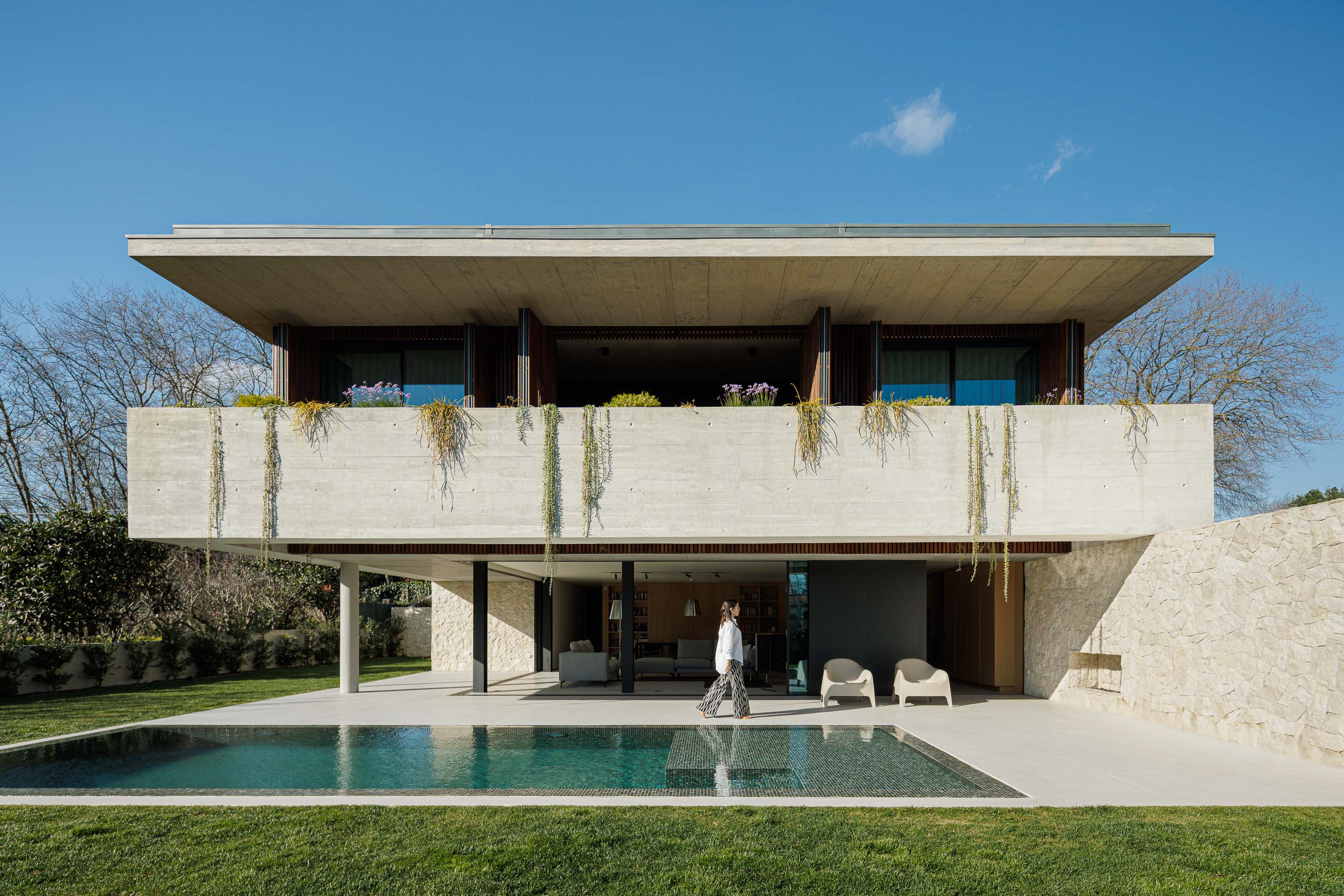 Exterior: Fachada de betão aparente e madeira, com piscina e relvado. — Casa M arquitetura silverline em Vila Nova de Gaia