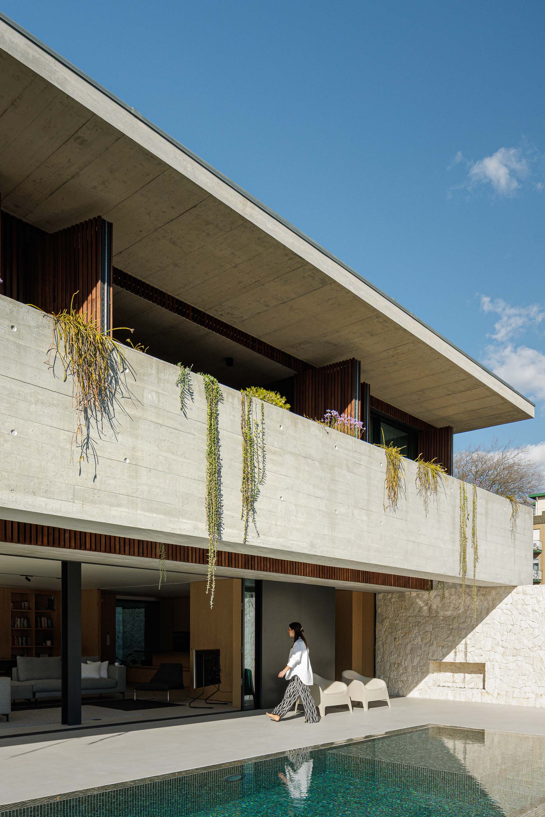 Exterior: Fachada de betão aparente e madeira, com piscina e relvado. — Casa M arquitetura silverline em Vila Nova de Gaia