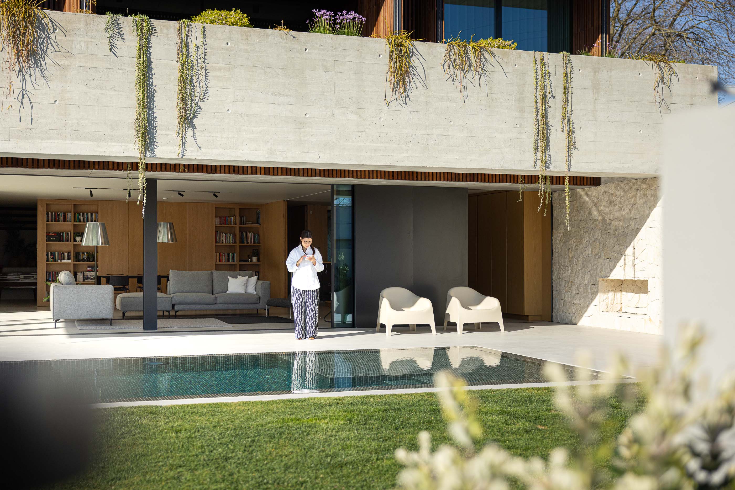 Exterior: Piscina com relvado e sala de estar com sofás e estantes. — Casa M arquitetura silverline em Vila Nova de Gaia