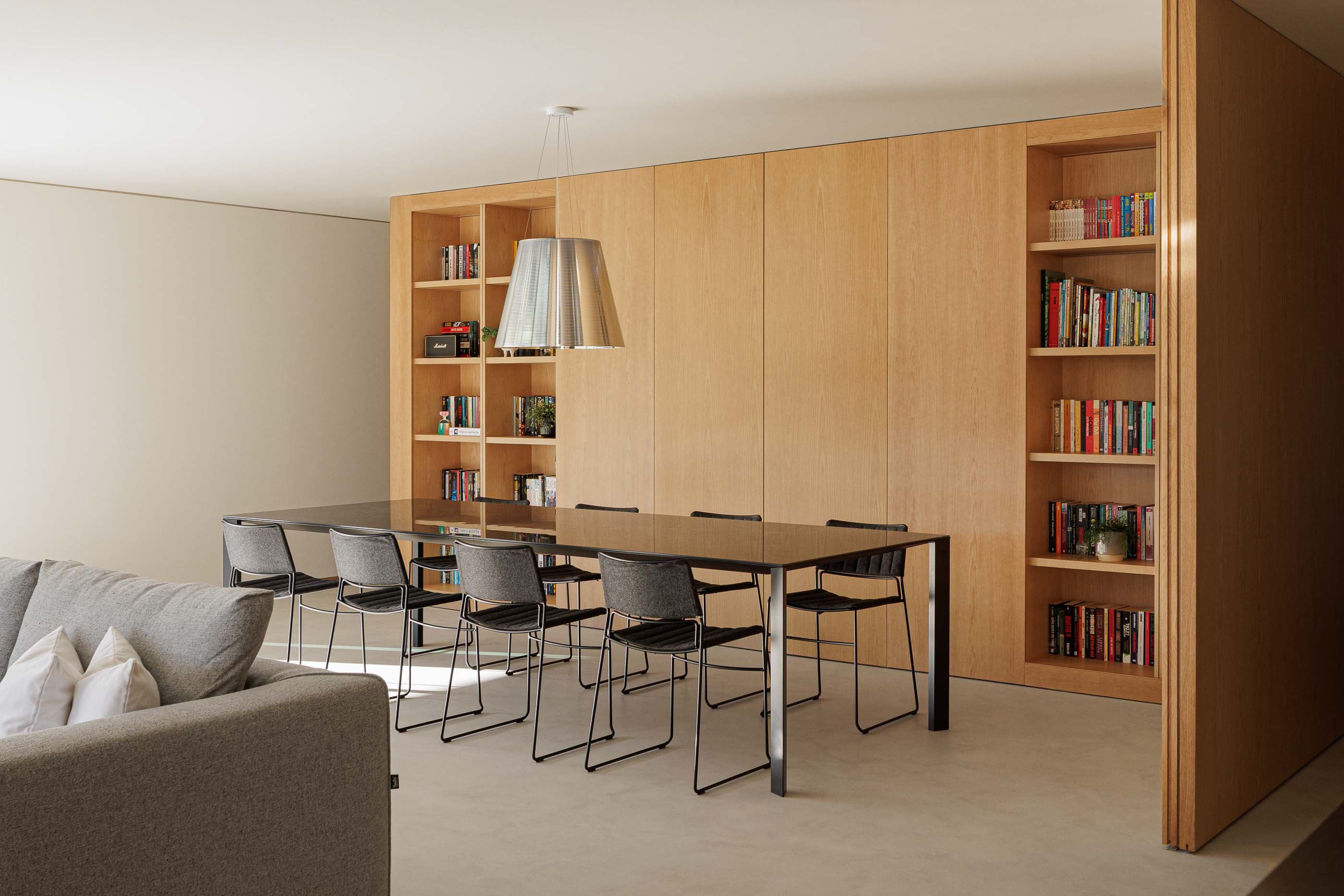Sala de jantar: Mesa de jantar preta com cadeiras cinzentas e estantes em madeira. — Casa M arquitetura silverline em Vila Nova de Gaia