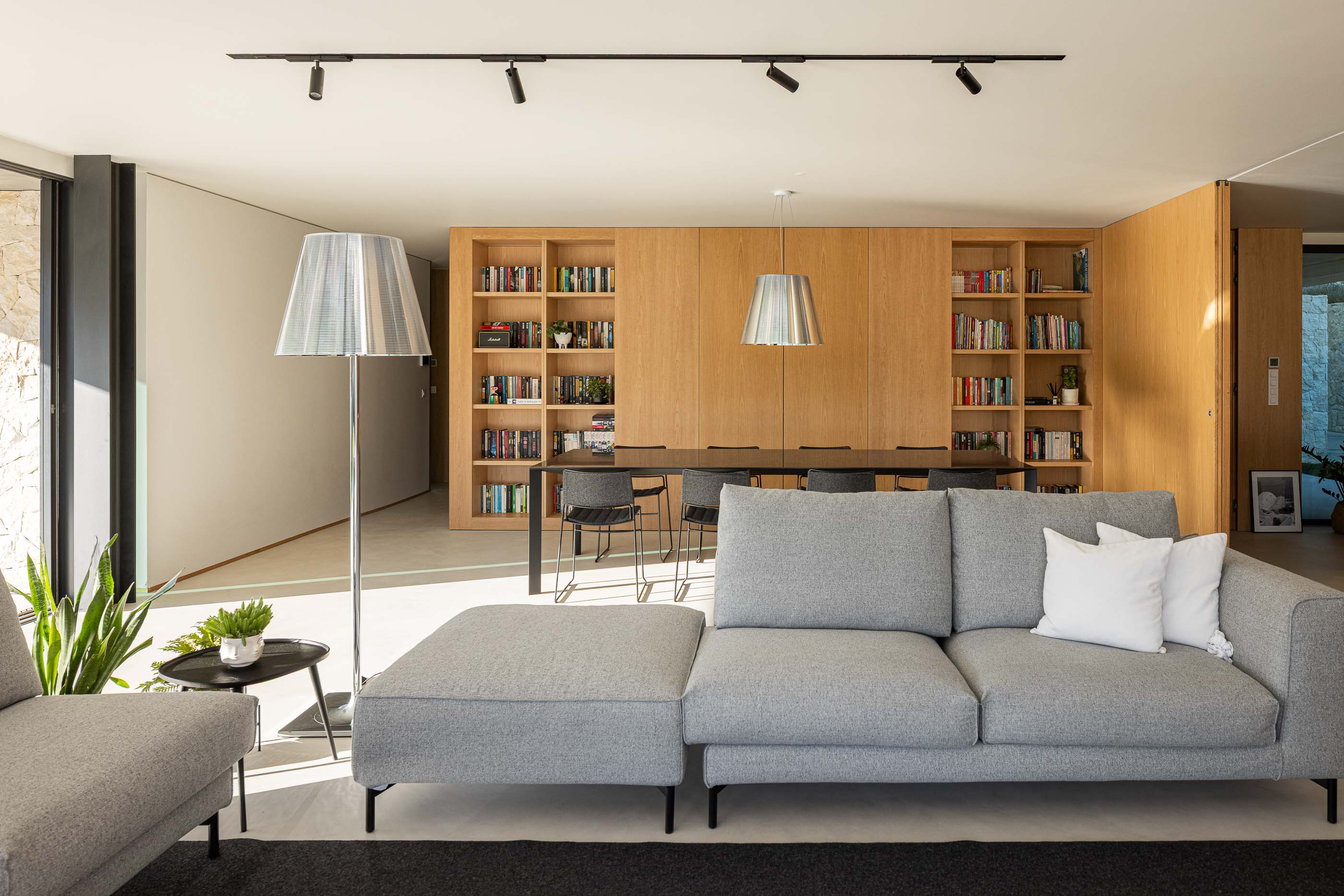 Sala de estar: Sofá cinzento, mesa de apoio preta e estantes em madeira. — Casa M arquitetura silverline em Vila Nova de Gaia