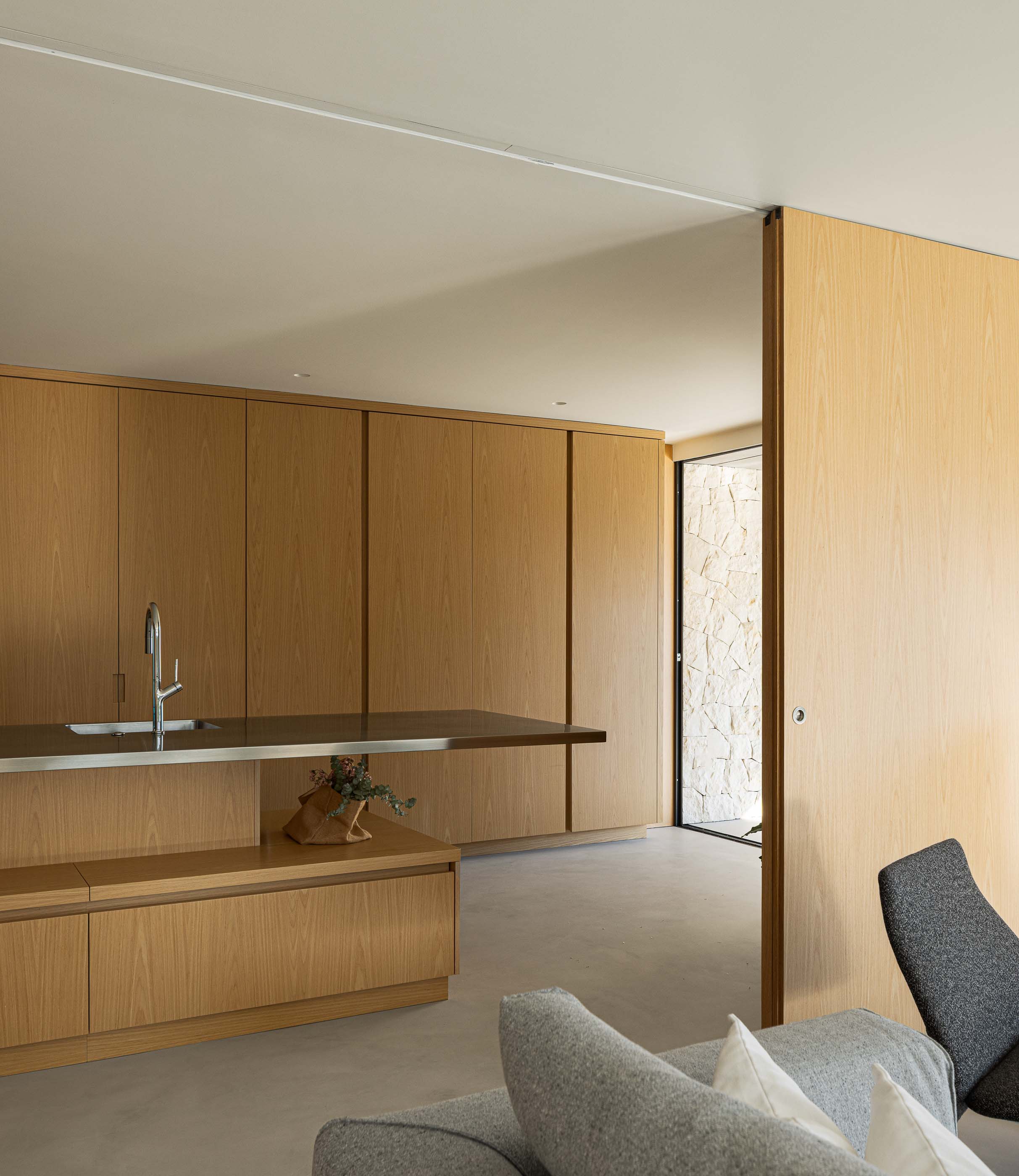 Cozinha: Ilha com lavatório em inox e armários em madeira. — Casa M arquitetura silverline em Vila Nova de Gaia