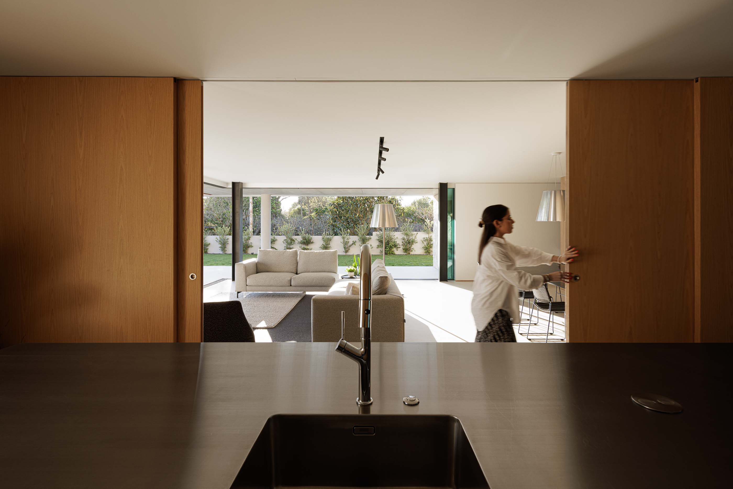 Cozinha: Vista da cozinha para a sala de estar com porta de correr em madeira. — Casa M arquitetura silverline em Vila Nova de Gaia