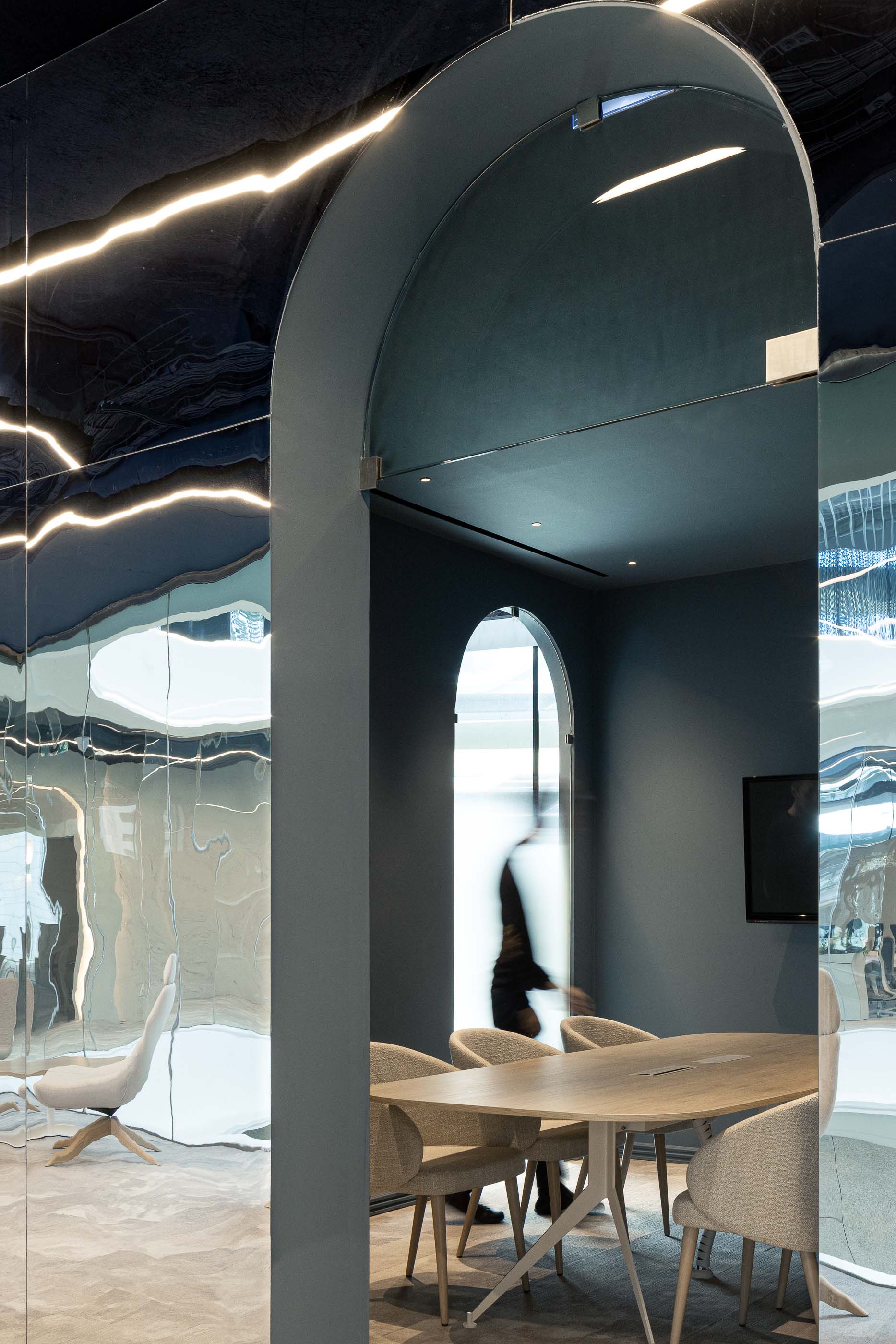 Sala de Reuniões: Porta em arco espelhada, mesa de madeira clara e cadeiras estofadas em tecido neutro. — Oporto MAZARS offices arquitetura GRAU.ZERO Arquitectura em Porto