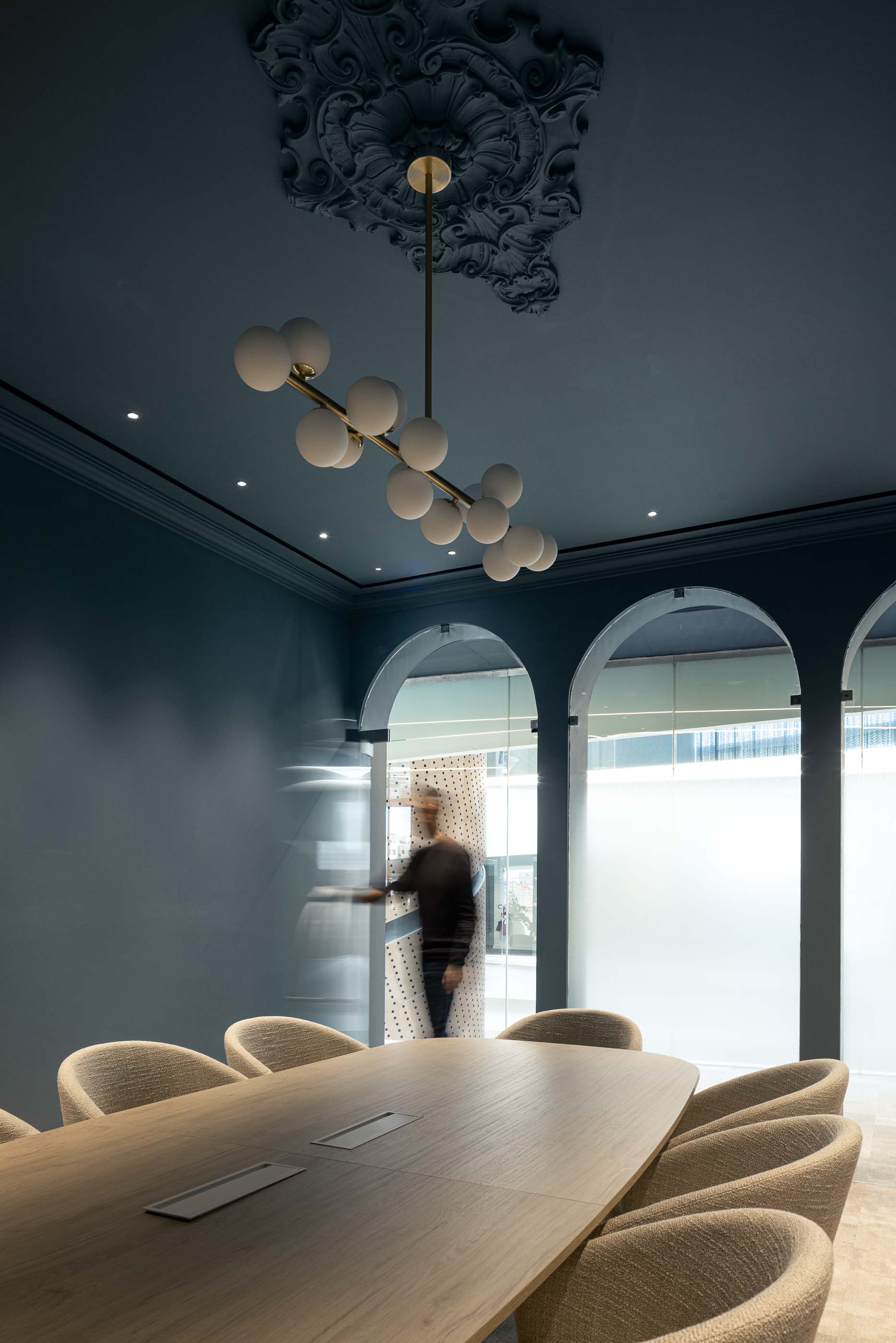 Sala de Reuniões: Mesa de madeira clara, cadeiras estofadas e candeeiro de teto esférico, em sala azul clássica. — Oporto MAZARS offices arquitetura GRAU.ZERO Arquitectura em Porto