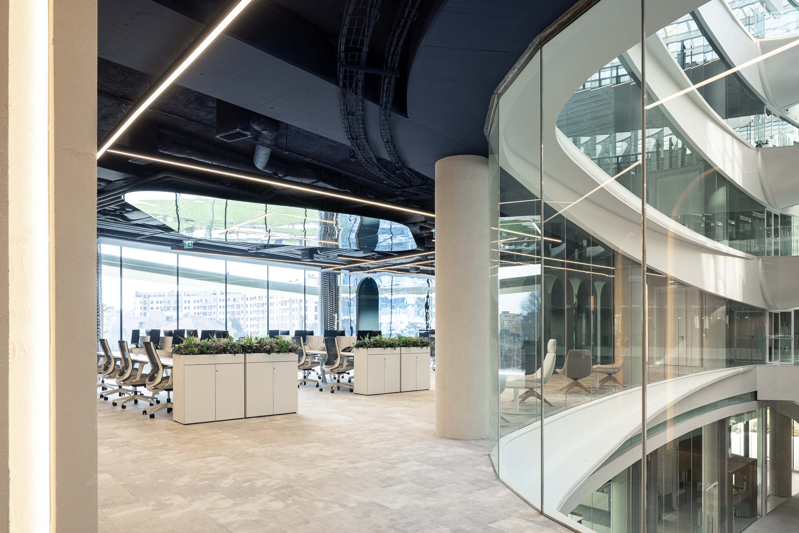 Escritório: Vista do átrio com divisórias de vidro e open space com secretárias brancas. — Oporto MAZARS offices arquitetura GRAU.ZERO Arquitectura em Porto