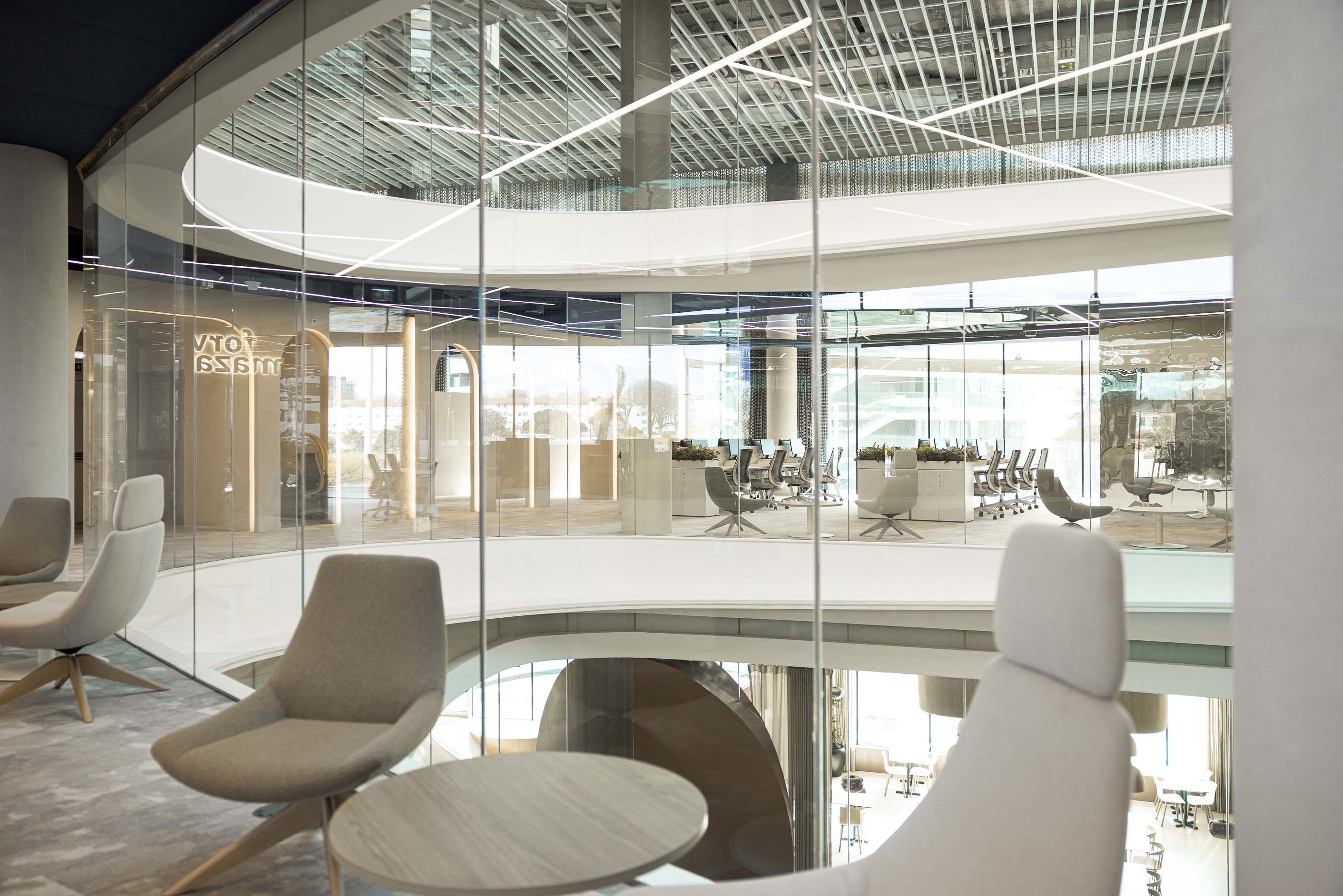 Escritório: Vista do átrio com divisórias de vidro e cadeiras de design em zona de descanso. — Oporto MAZARS offices arquitetura GRAU.ZERO Arquitectura em Porto