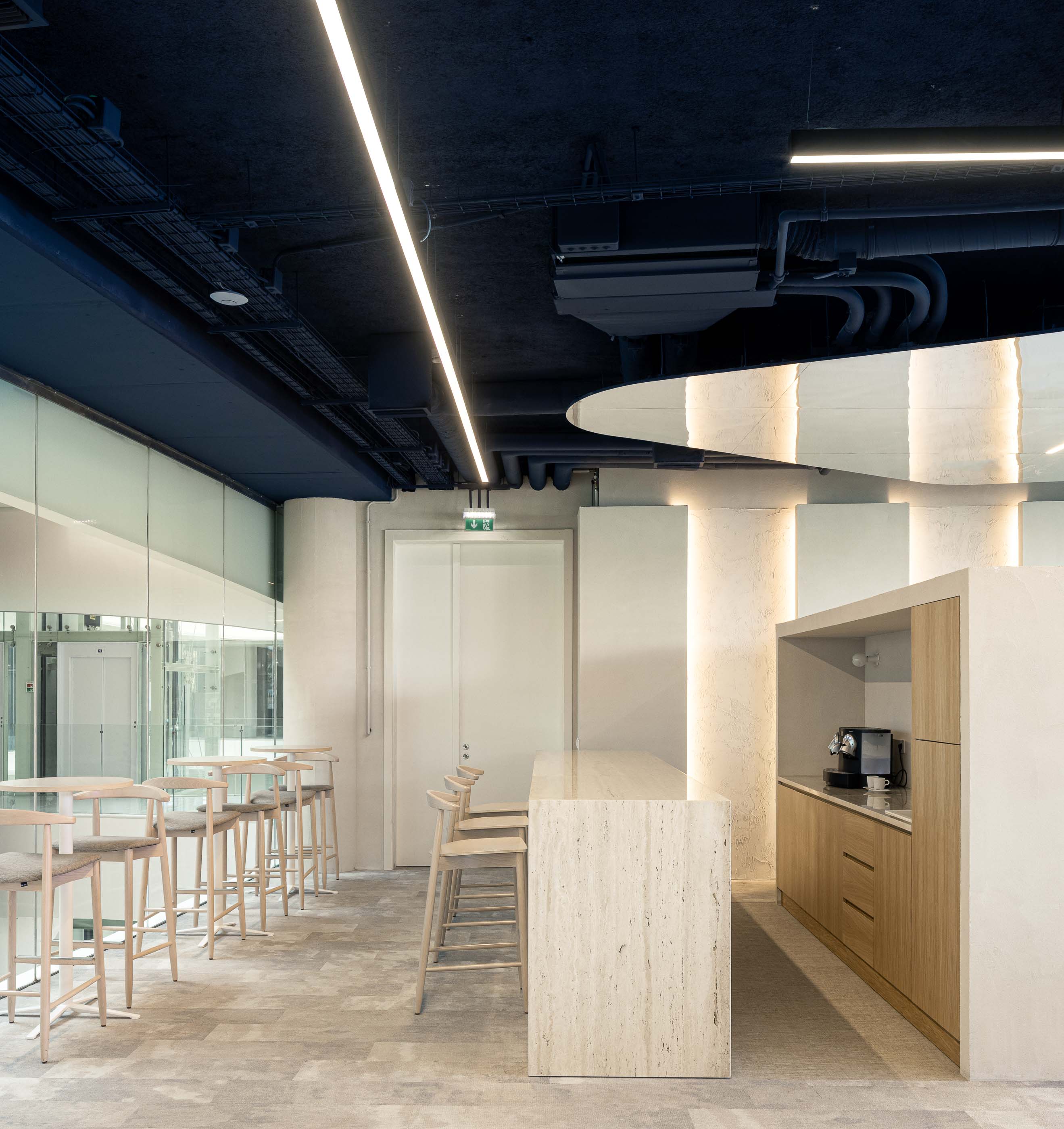 Copa: Balcão alto em travertino, armários de madeira clara e alcatifa cinzenta. — Oporto MAZARS offices arquitetura GRAU.ZERO Arquitectura em Porto