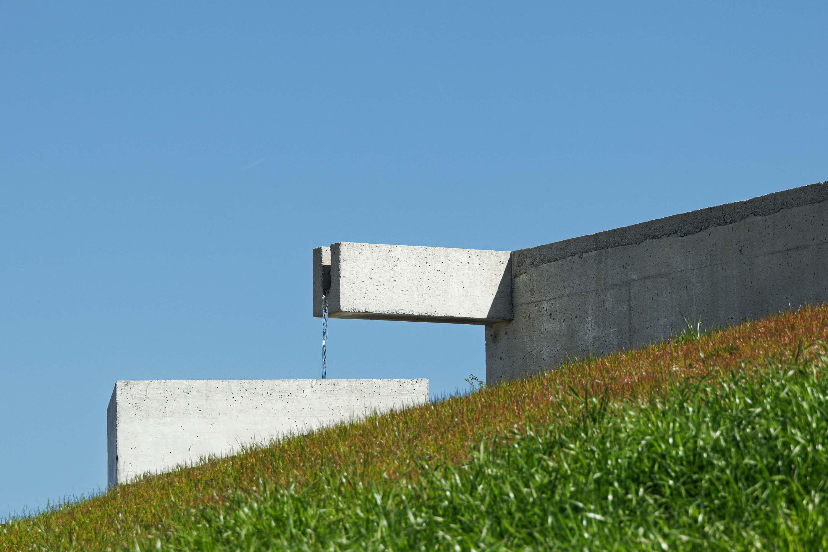 Exterior: Detalhe de um bebedouro em betão, com água a correr, integrado no muro de suporte. — Pedrantil House arquitetura Helder da Rocha Arquitectos em Penafiel