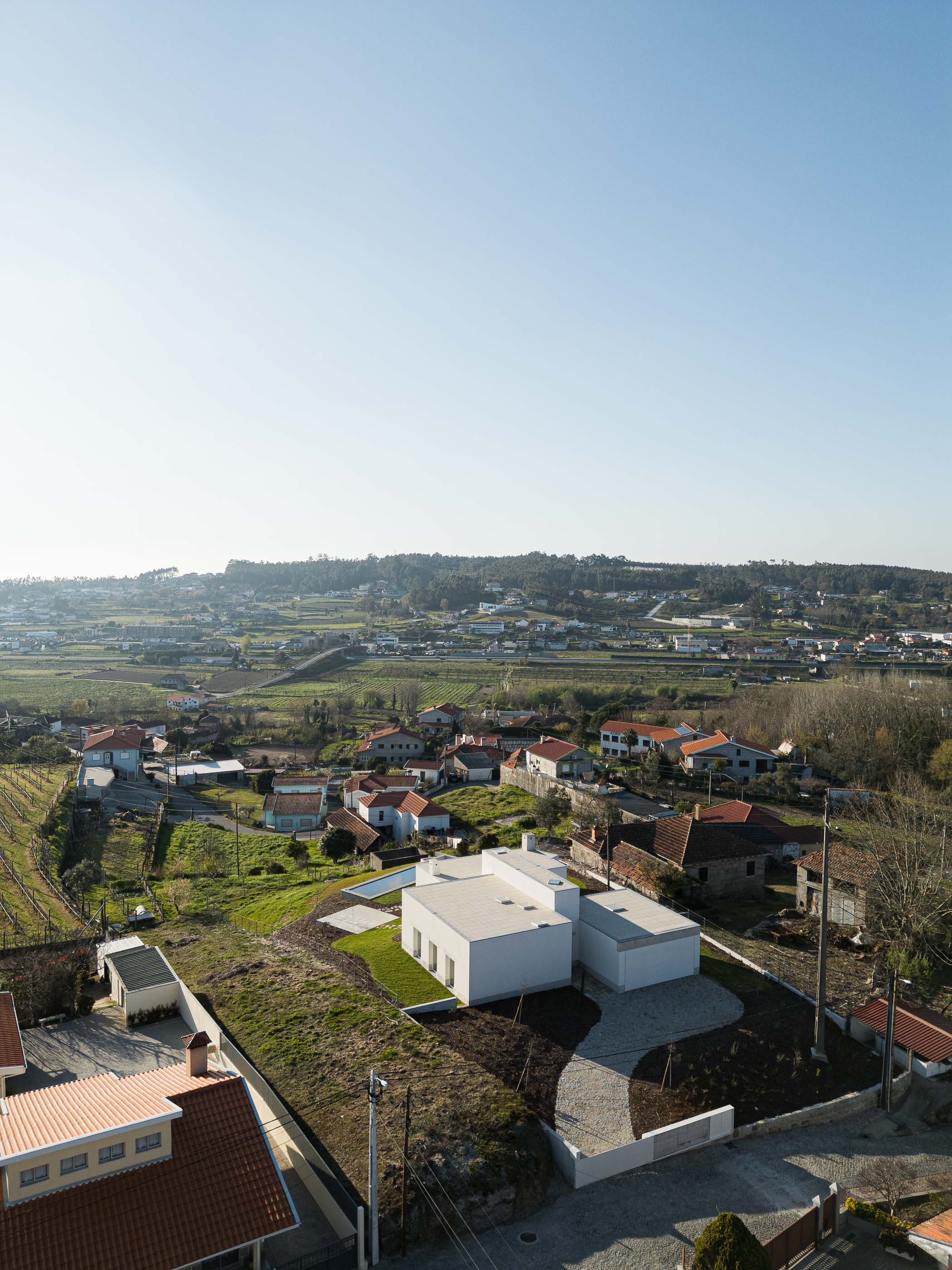 Exterior: Vista aérea da casa, com piscina, jardim e acesso pavimentado. — Pedrantil House arquitetura Helder da Rocha Arquitectos em Penafiel