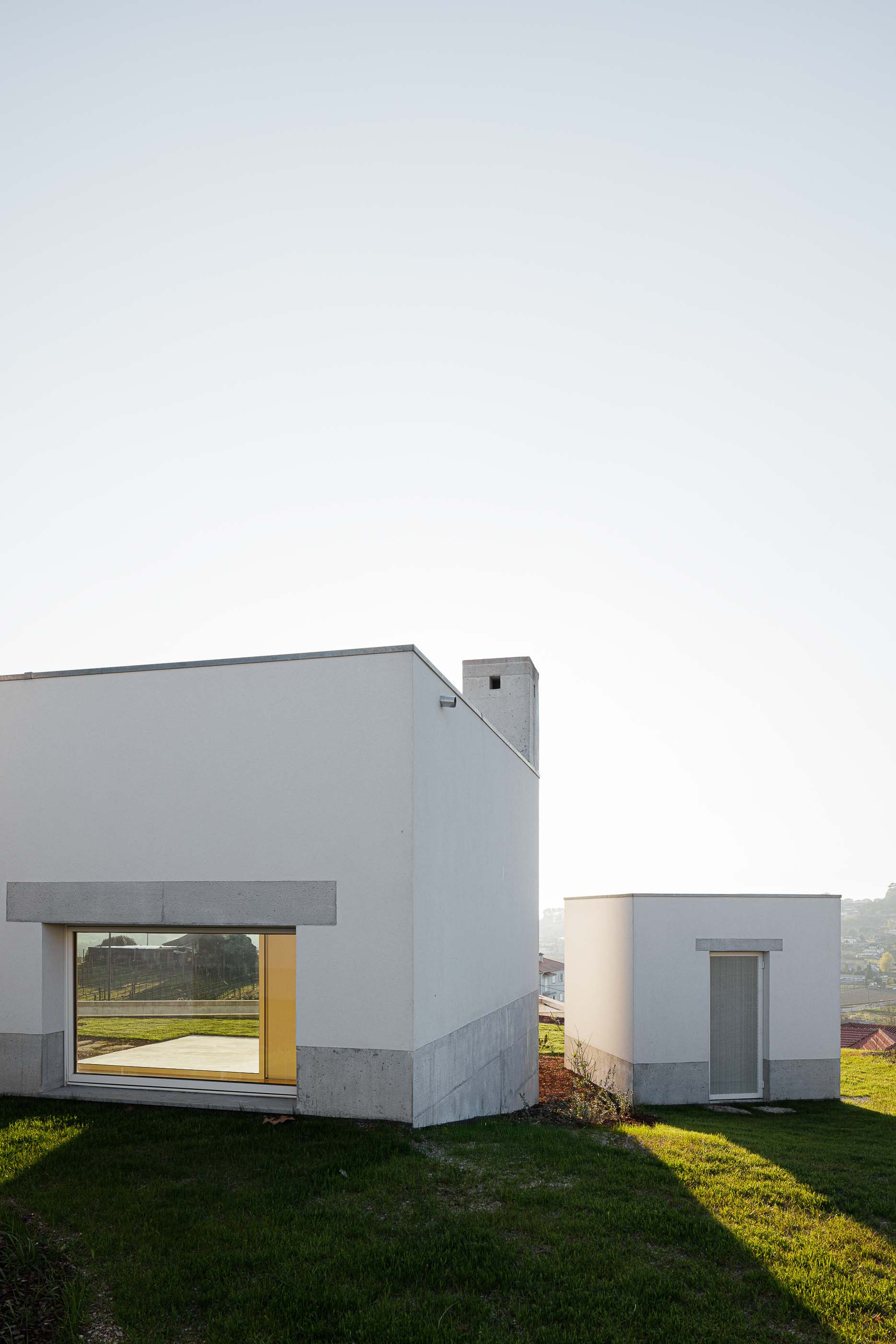 Exterior: Vista lateral da casa, com volumes distintos e janelas emolduradas em betão. — Pedrantil House arquitetura Helder da Rocha Arquitectos em Penafiel