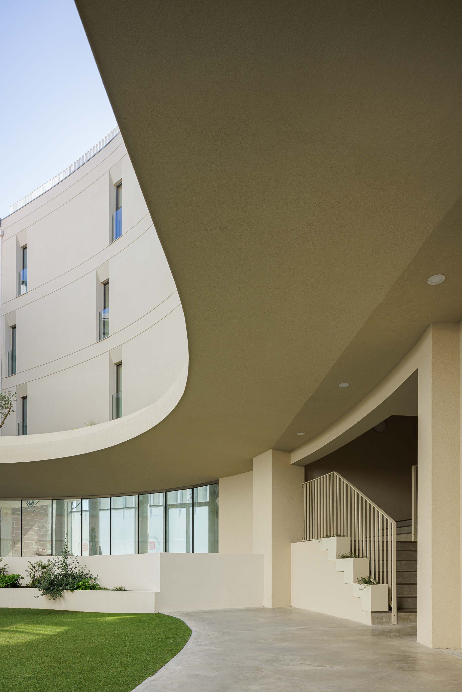 Pátio interior do Edifício Estação, com passadiço curvo, jardim e escadas com floreiras. — Edifício Estação arquitetura Sónia Cruz Arquitectura em Aveiro