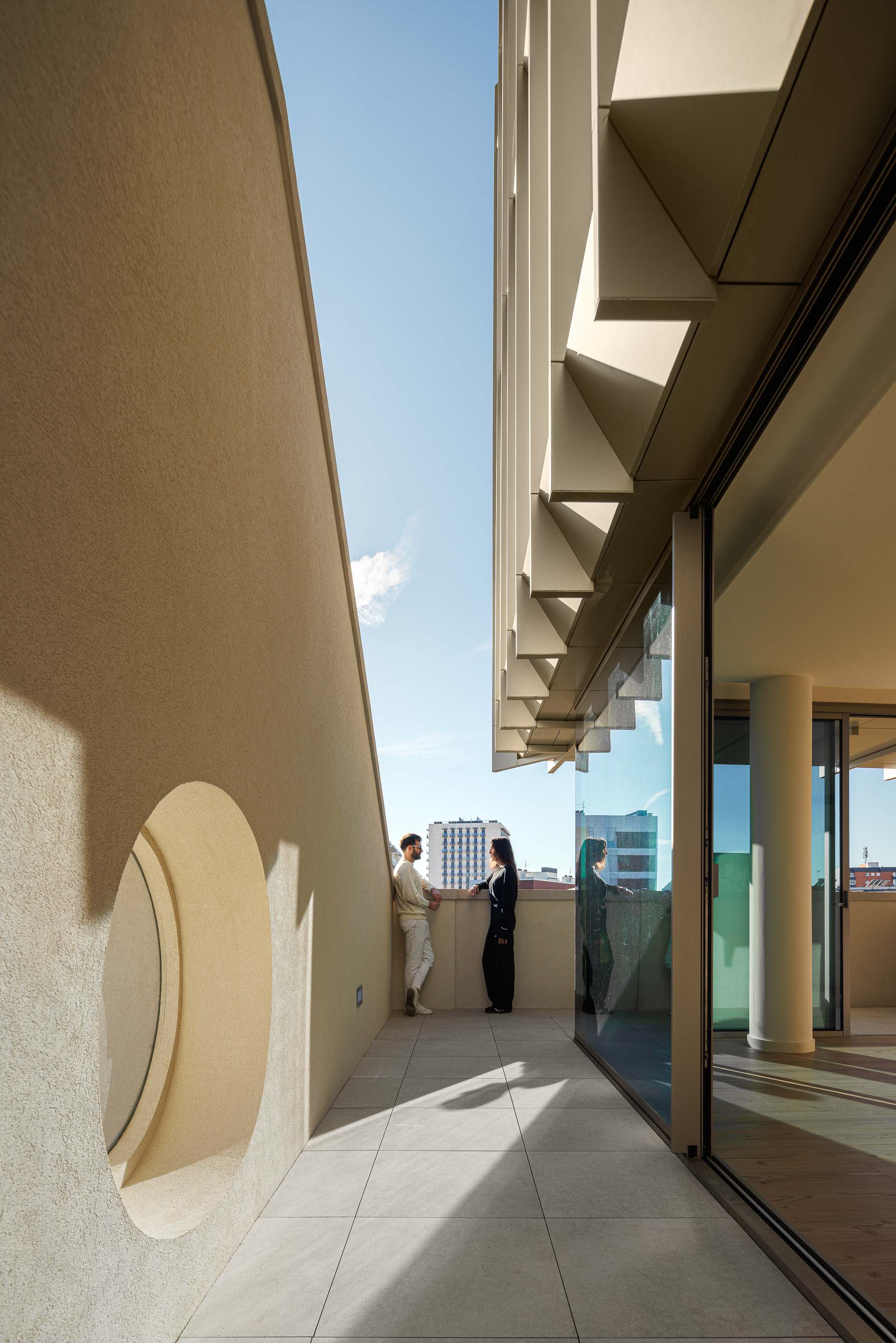 Corredor com pavimento de madeira e paredes brancas, com porta ao fundo. — Edifício Estação arquitetura Sónia Cruz Arquitectura em Aveiro