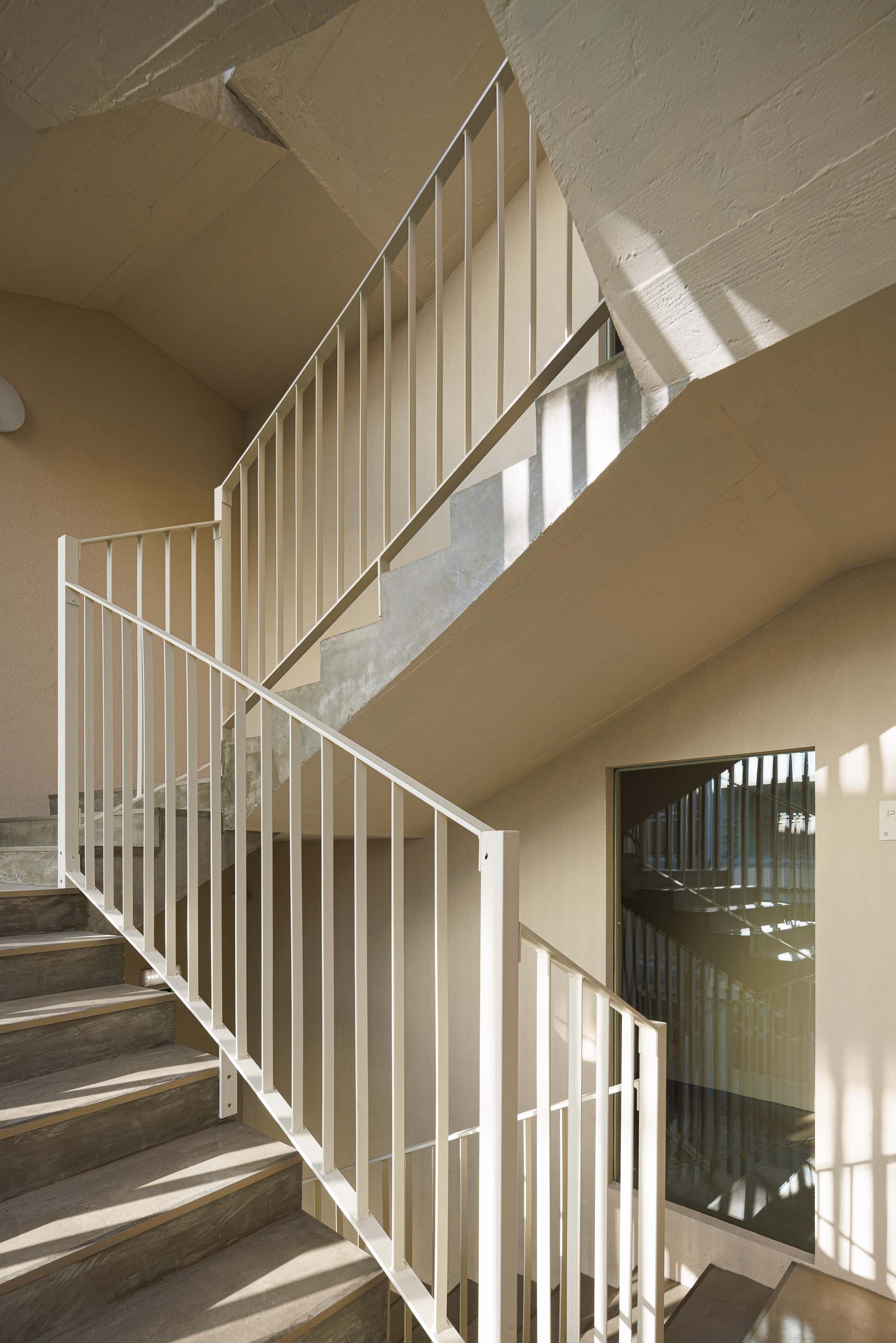 Pátio interior do Edifício Estação, com escadas, elevador e fachada curva com ripas verticais. — Edifício Estação arquitetura Sónia Cruz Arquitectura em Aveiro