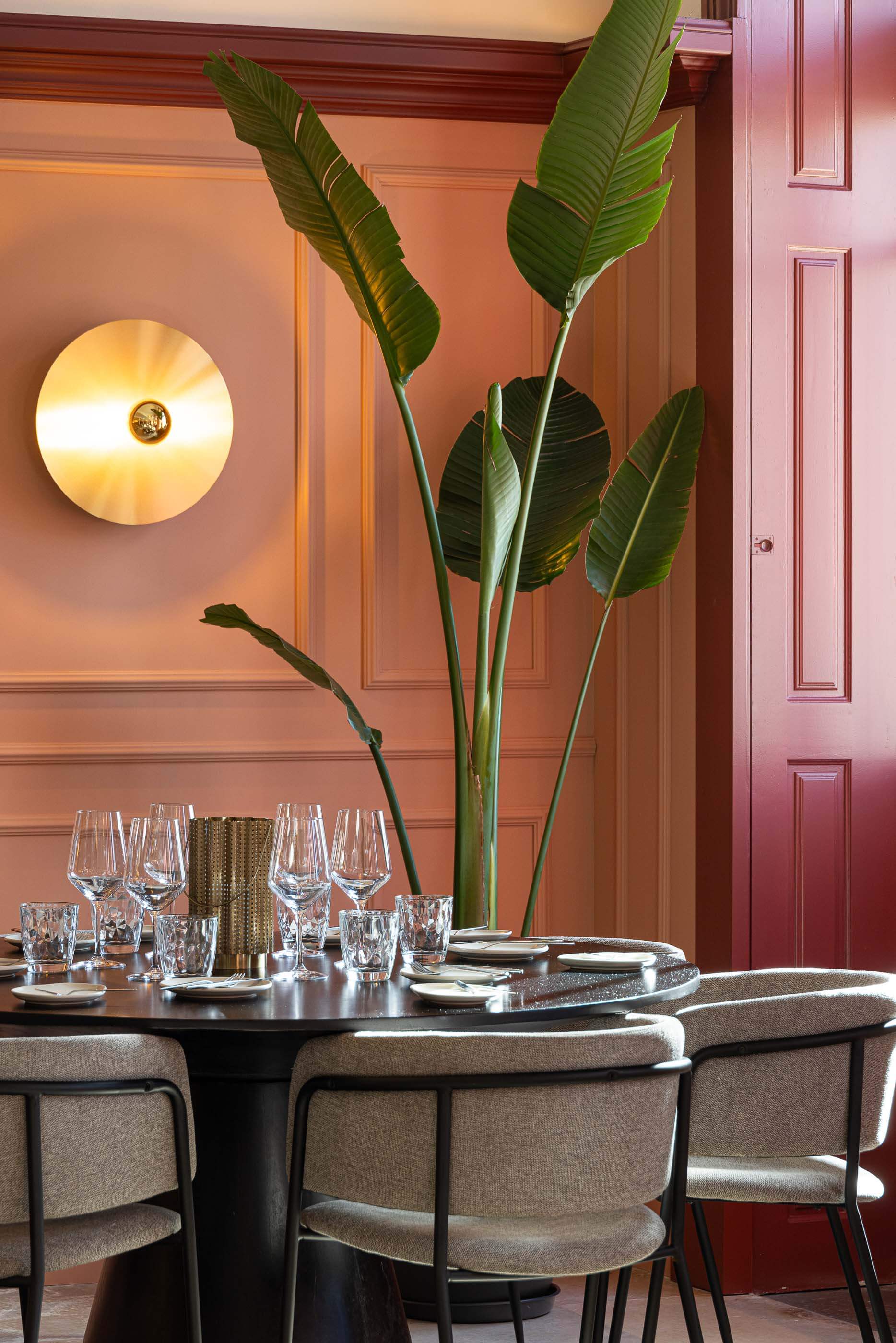 Restaurante: Mesa redonda com cadeiras cinzentas, louça elegante e candeeiro de parede dourado, num ambiente clássico com painéis cor-de-rosa. — Restaurante Concerto arquitetura MiMool Arquitectura & Interiores em vila do conde