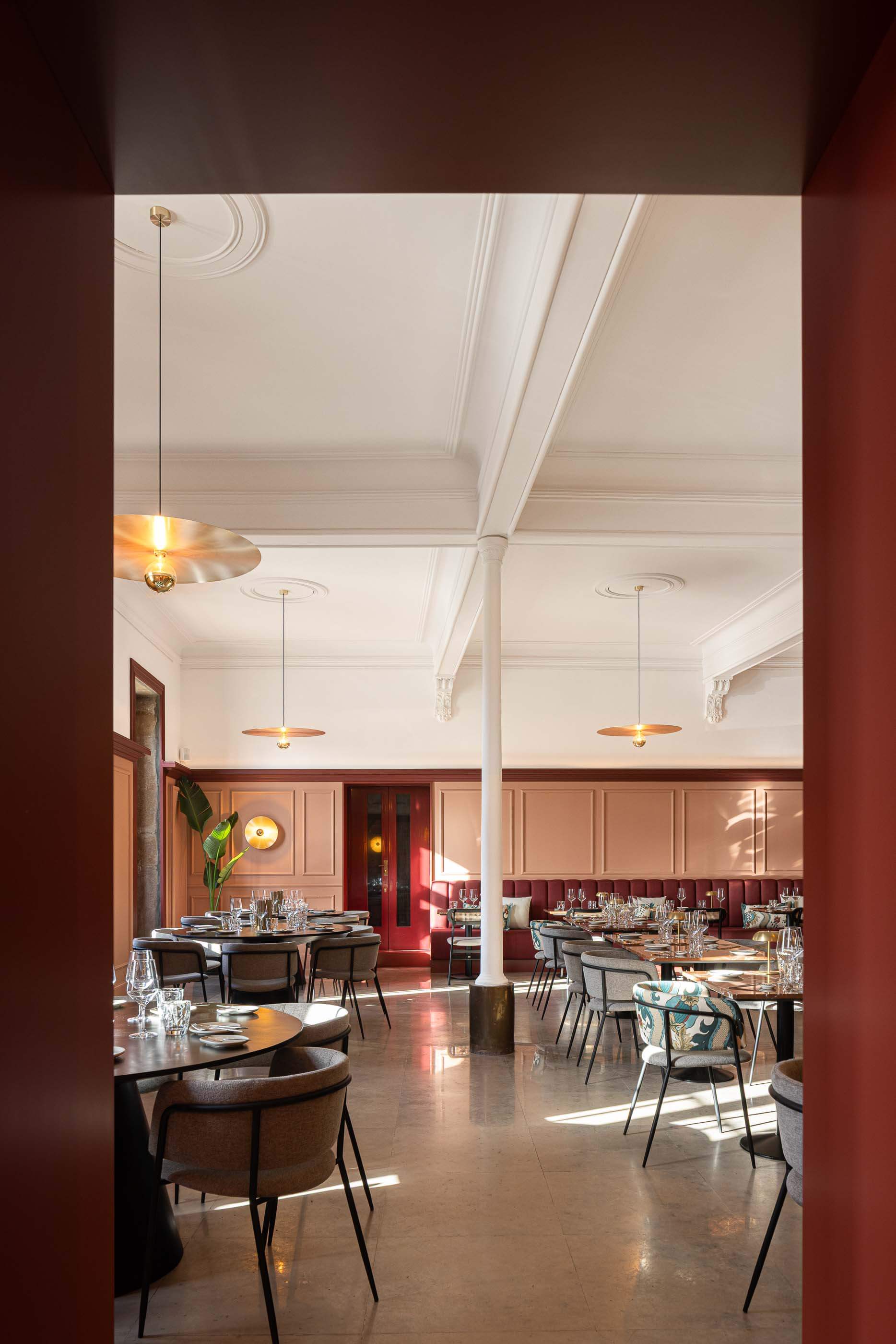 Restaurante: Vista geral do salão com mesas, cadeiras, colunas clássicas e candeeiros suspensos dourados, pavimento em pedra e luz natural. — Restaurante Concerto arquitetura MiMool Arquitectura & Interiores em vila do conde