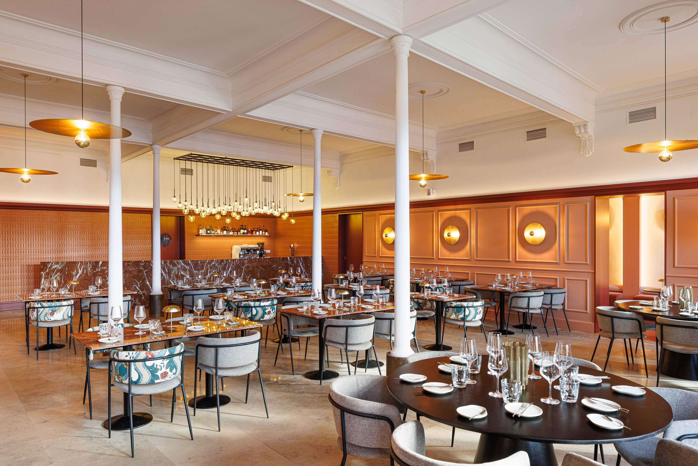 Restaurante: Salão amplo com mesas de mármore, cadeiras variadas, bar ao fundo e iluminação moderna suspensa. — Restaurante Concerto arquitetura MiMool Arquitectura & Interiores em vila do conde