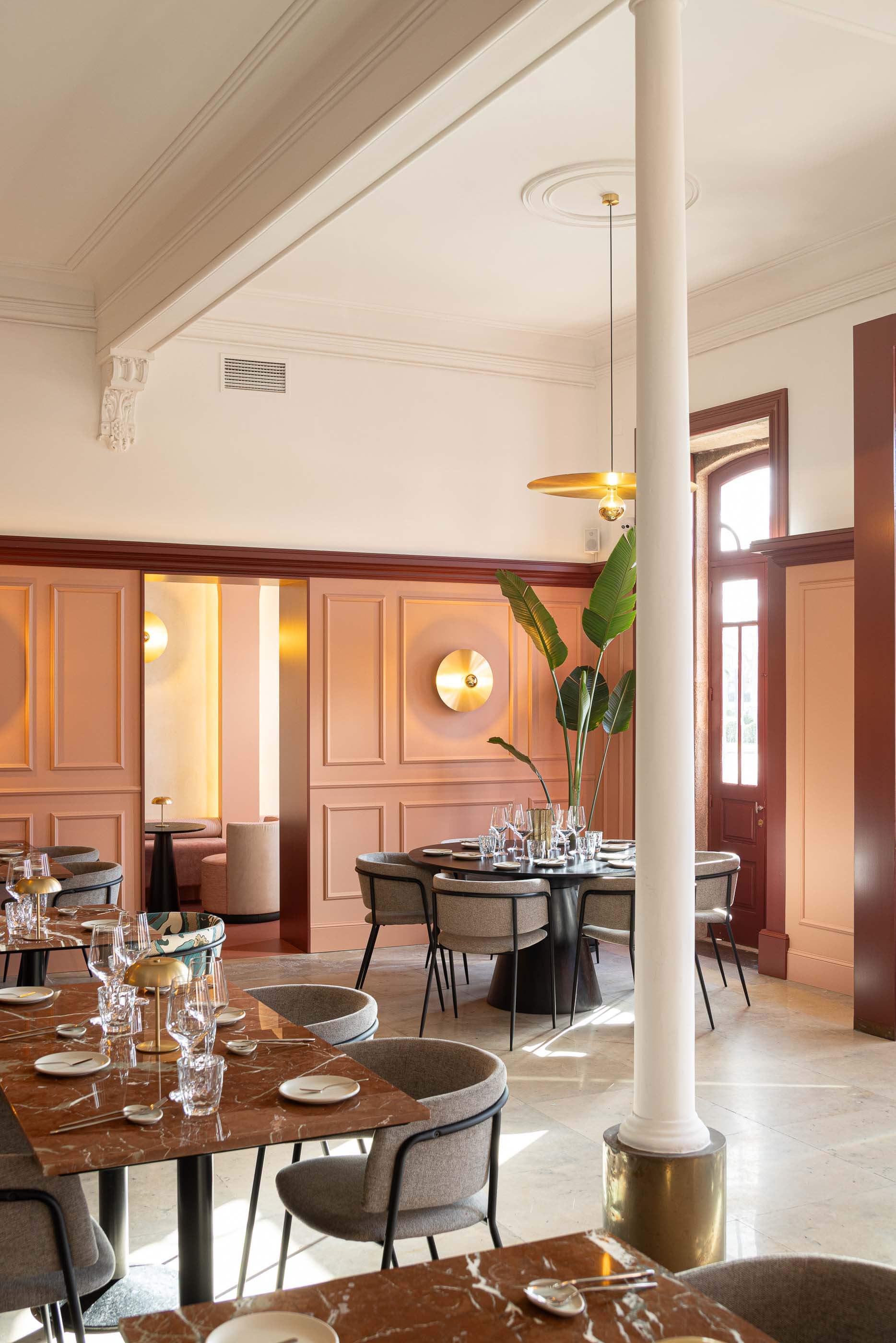 Restaurante: Perspectiva do salão com colunas brancas, mesas de mármore, cadeiras cinzentas e iluminação dourada. — Restaurante Concerto arquitetura MiMool Arquitectura & Interiores em vila do conde
