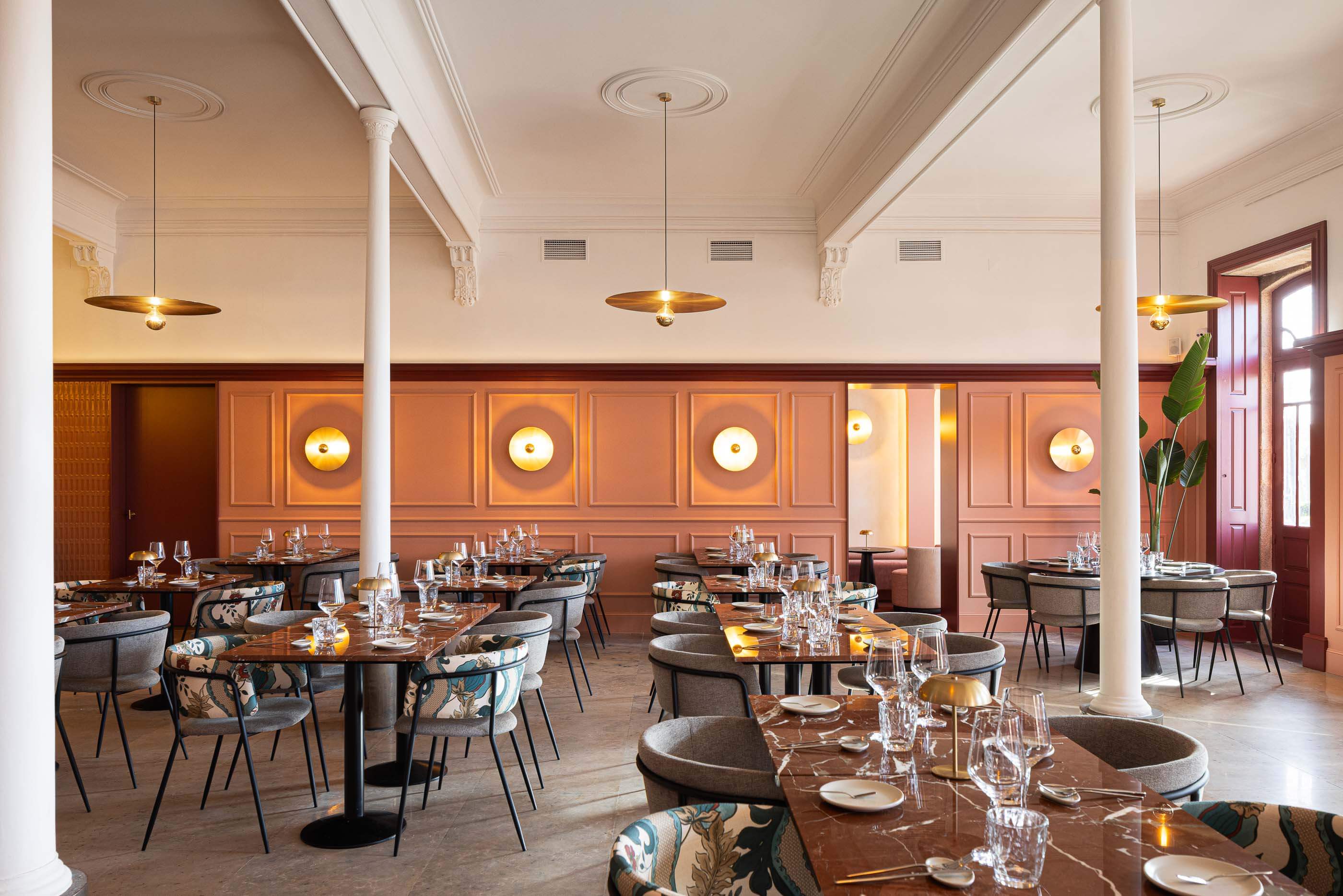 Restaurante: Vista geral do salão com mesas de mármore, cadeiras coloridas, candeeiros dourados e painéis cor-de-rosa. — Restaurante Concerto arquitetura MiMool Arquitectura & Interiores em vila do conde