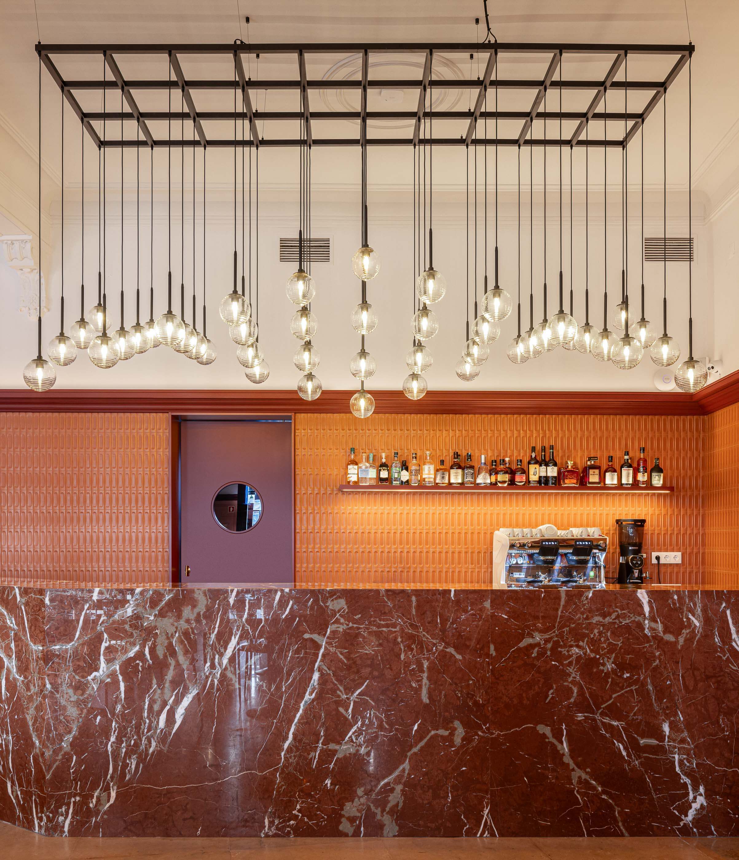 Restaurante: Detalhe do bar com balcão de mármore, parede texturada e iluminação suspensa. — Restaurante Concerto arquitetura MiMool Arquitectura & Interiores em vila do conde