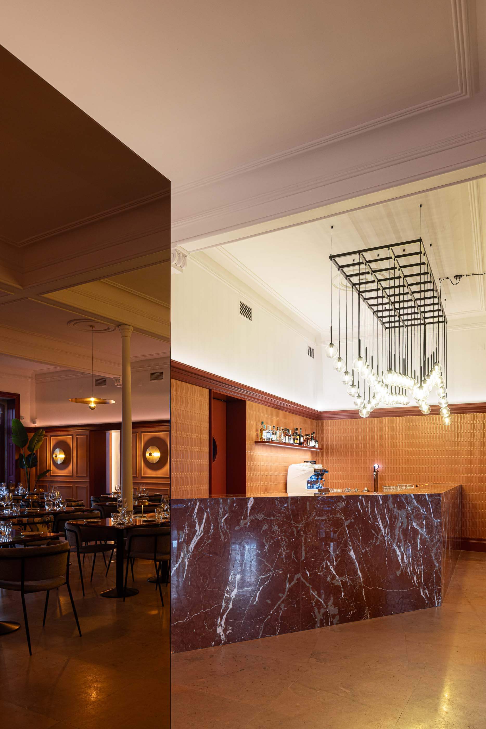 Restaurante: Vista geral do salão com bar, mesas de mármore, cadeiras e espelho refletindo o espaço. — Restaurante Concerto arquitetura MiMool Arquitectura & Interiores em vila do conde