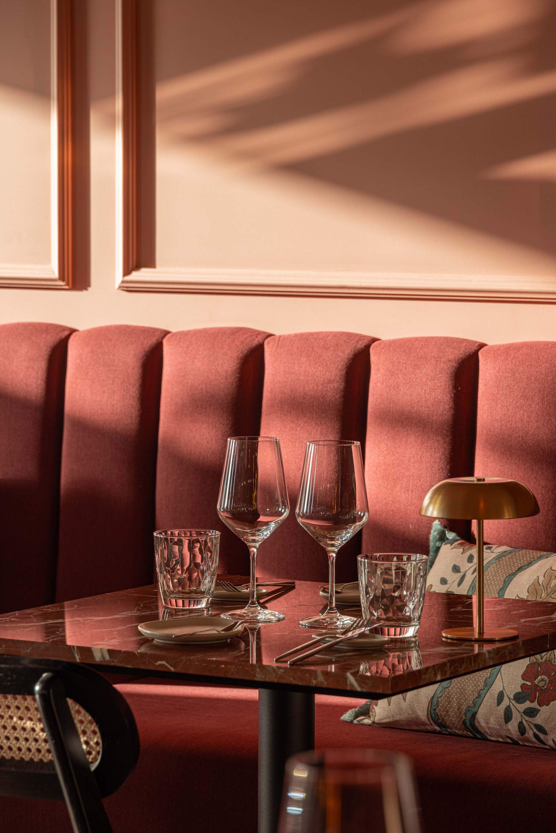 Restaurante: Detalhe de mesa com tampo de mármore, cadeiras, louça e banco almofadado cor-de-vinho. — Restaurante Concerto arquitetura MiMool Arquitectura & Interiores em vila do conde