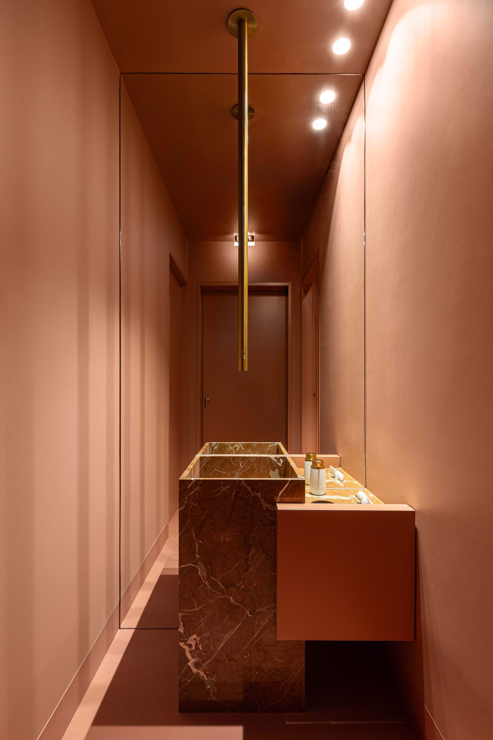 Casa de banho: Corredor com lavatório de mármore, espelho amplo e iluminação ambiente. — Restaurante Concerto arquitetura MiMool Arquitectura & Interiores em vila do conde