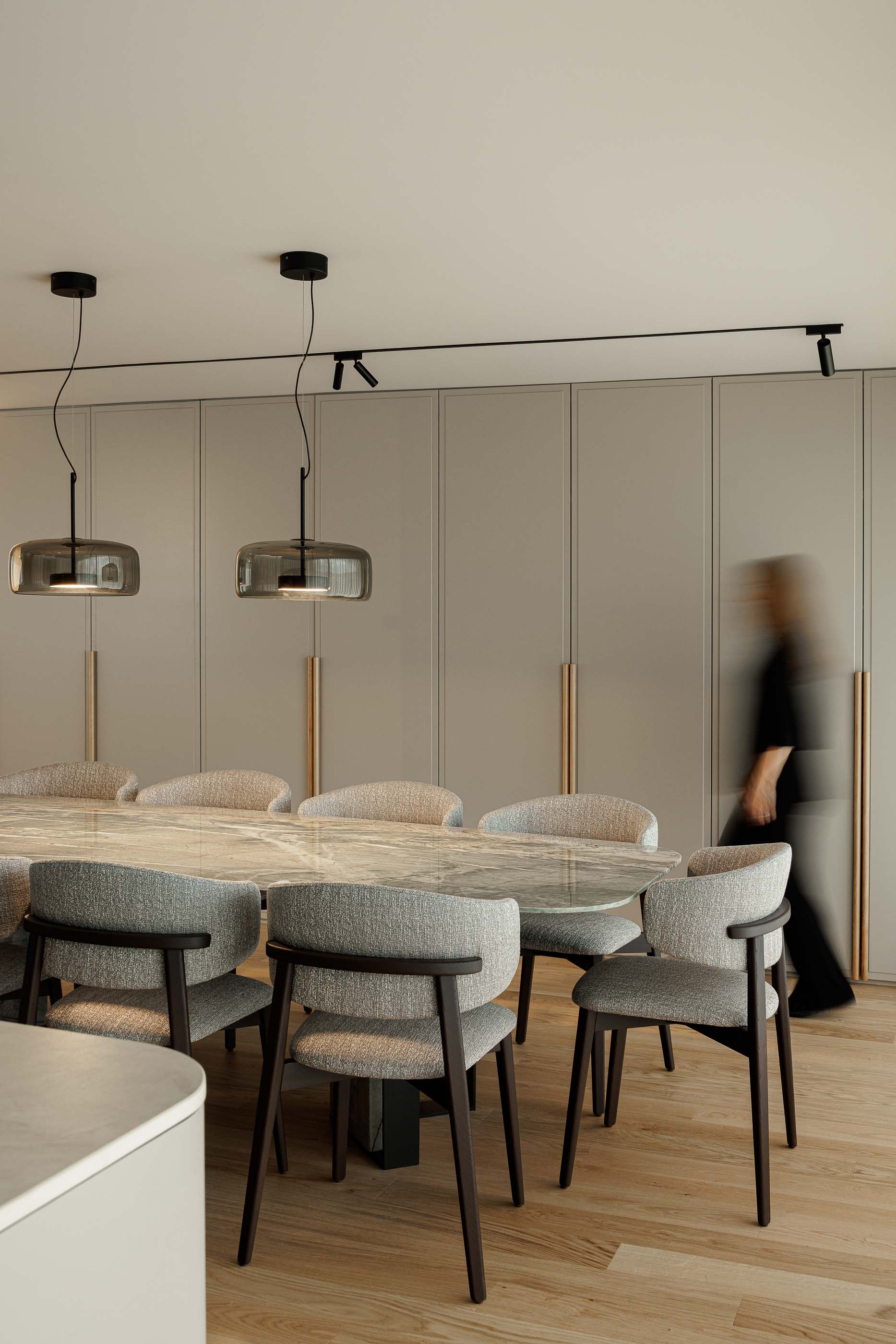 Sala de jantar com mesa em mármore e cadeiras estofadas. Armários embutidos ao fundo e pavimento em madeira. — Casa Linho arquitetura Paula Novais Arquitectos em Fafe
