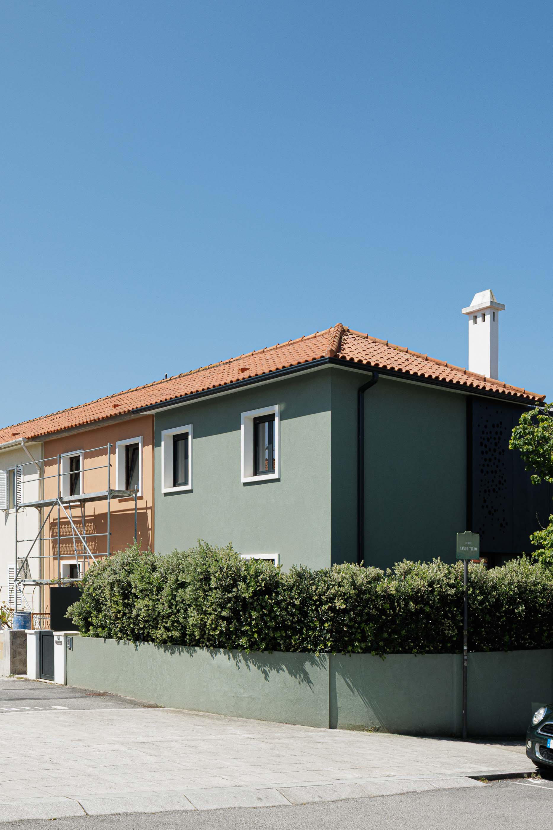 Exterior: Vista da casa verde com telhado de telha, anexo moderno em preto e jardim. Arquitetura renovada. — Casa Pi arquitetura ArquitectosRT em Porto