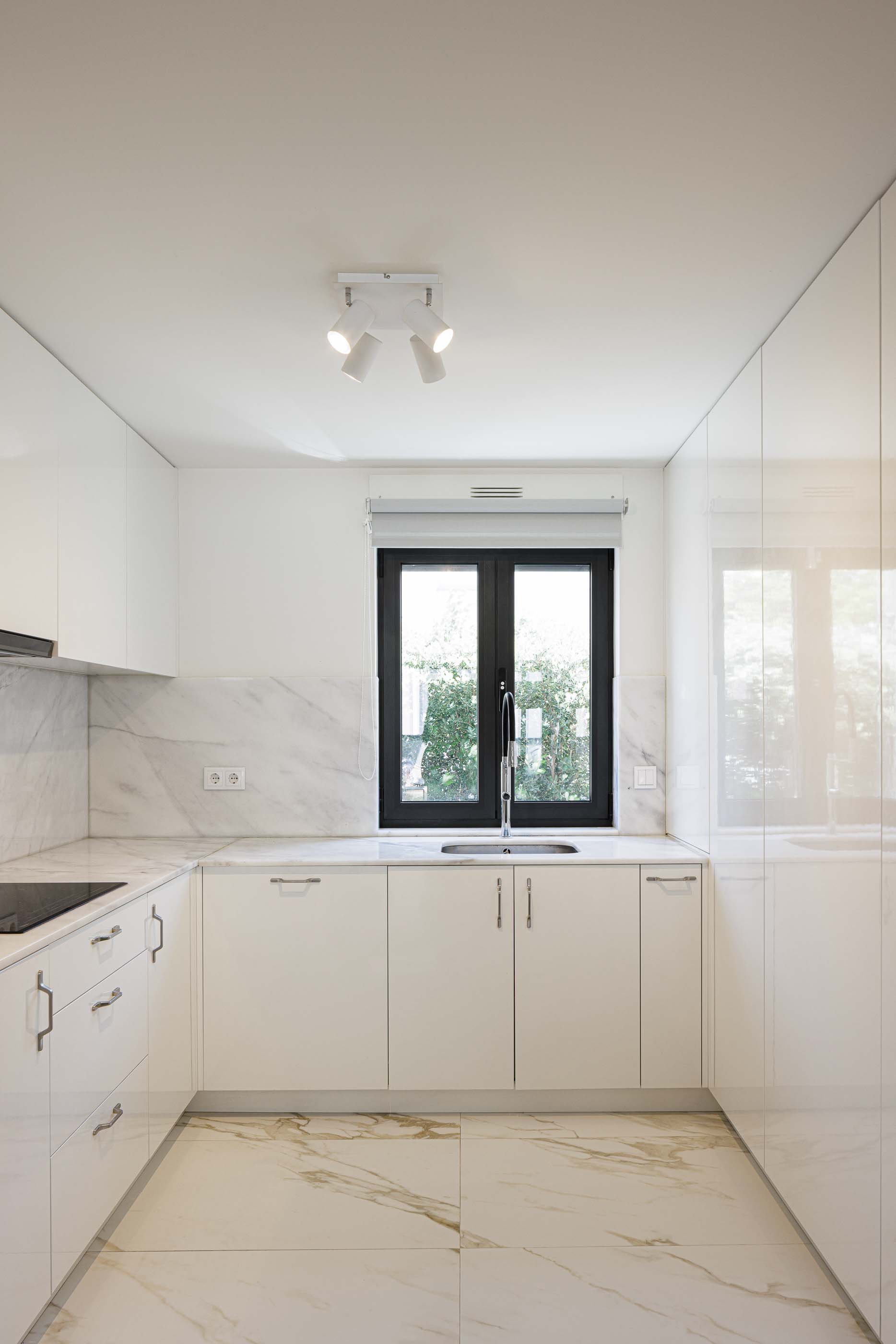 Cozinha: Cozinha moderna com armários brancos brilhantes, bancada em mármore e pavimento cerâmico claro. — Casa Pi arquitetura ArquitectosRT em Porto