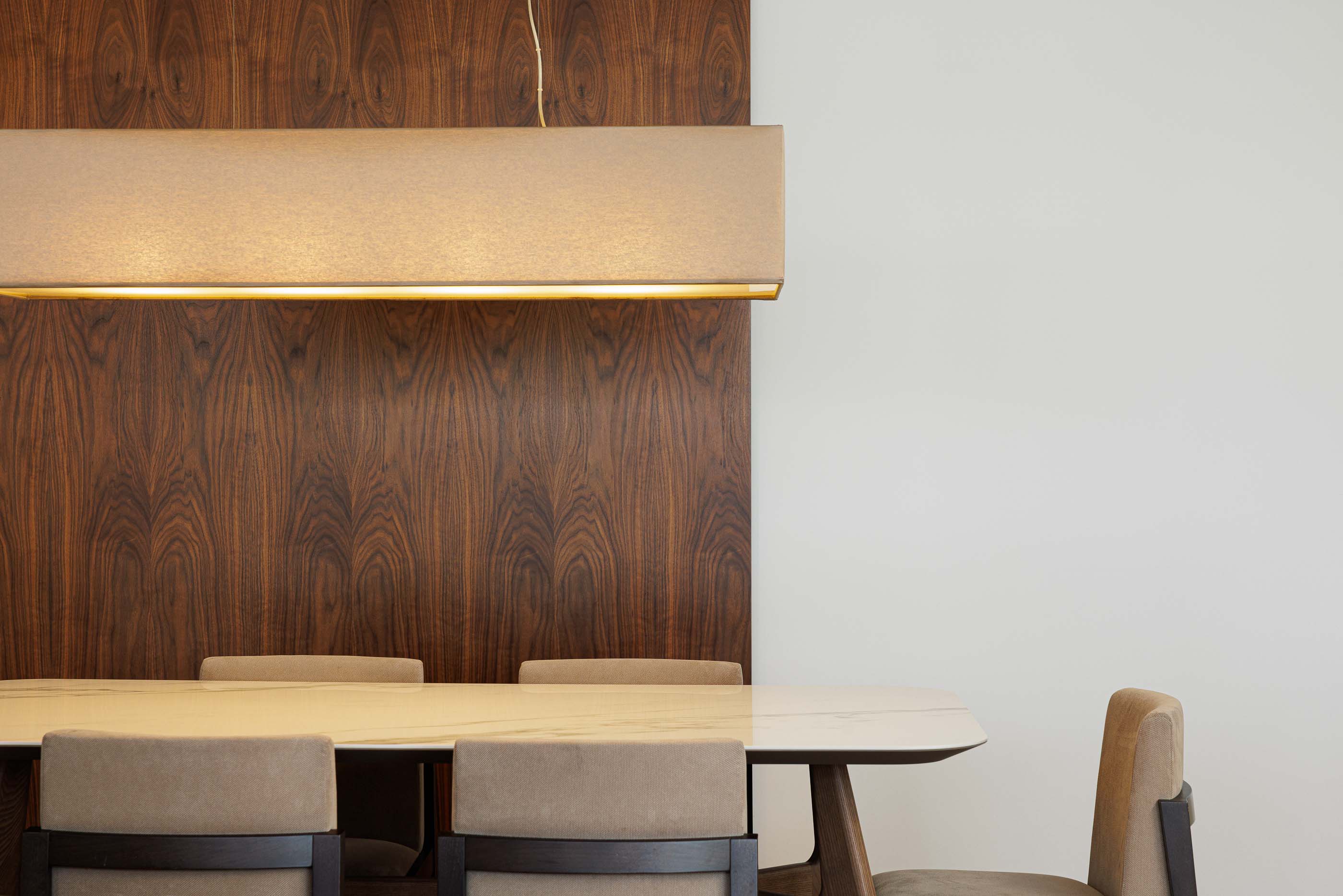 Sala de jantar: Detalhe da sala de jantar com mesa de mármore, cadeiras estofadas e parede revestida a madeira. — Casa Pi arquitetura ArquitectosRT em Porto