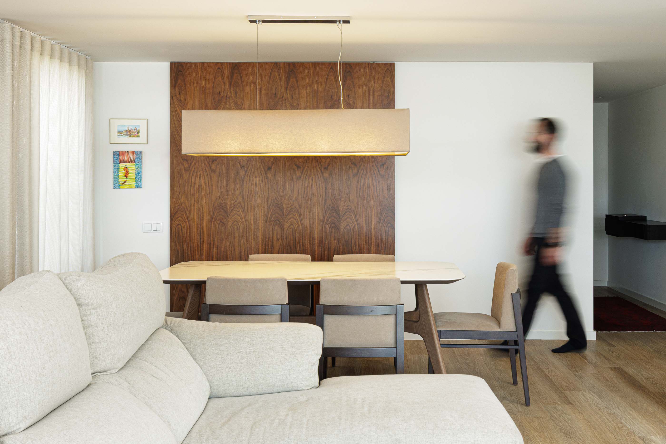 Sala de estar/Jantar: Sala de estar com sofá bege, mesa de jantar e parede em madeira. Pavimento em madeira clara. — Casa Pi arquitetura ArquitectosRT em Porto