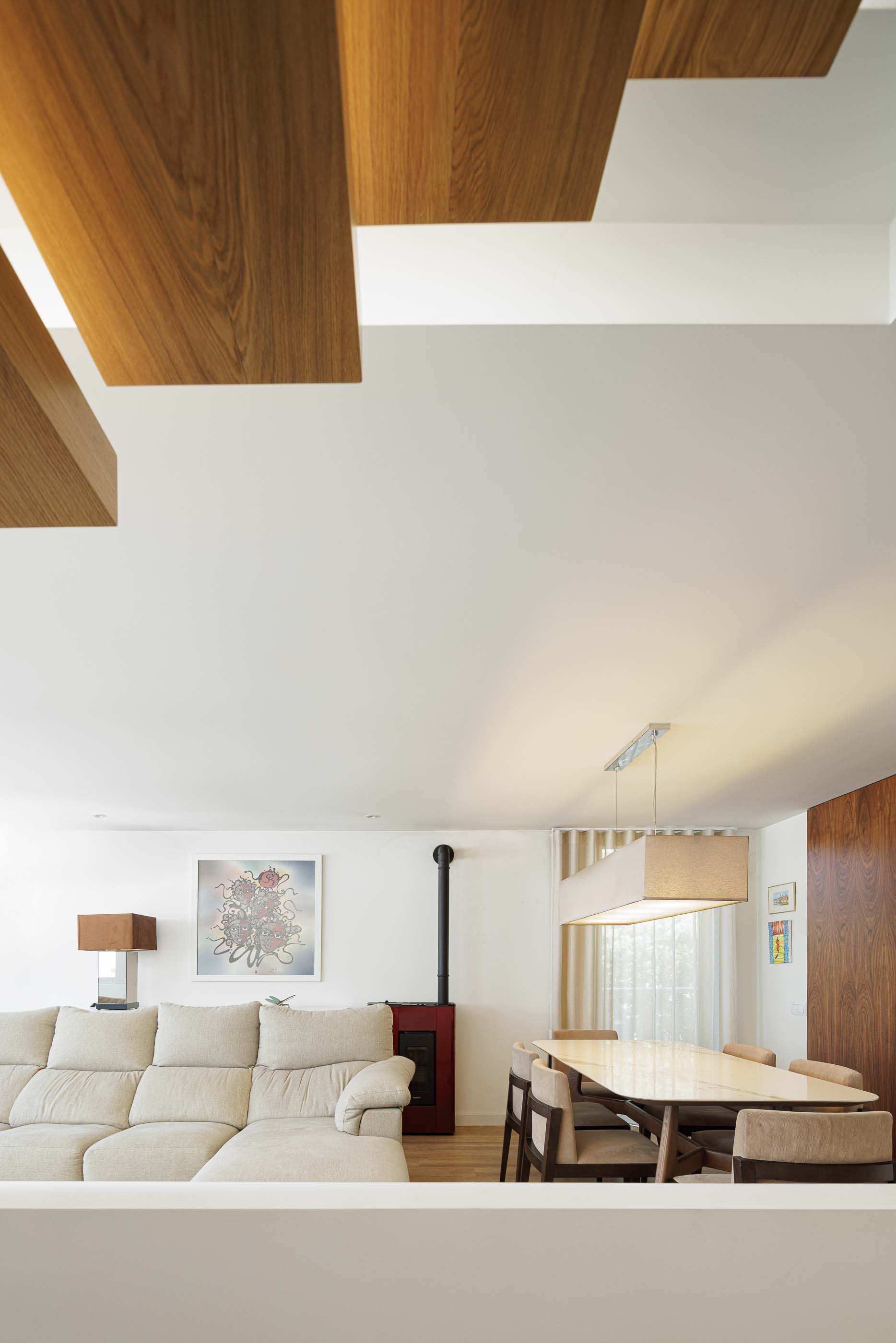 Sala de estar/Jantar: Vista da sala de estar com sofá, recuperador de calor vermelho e mesa de jantar. — Casa Pi arquitetura ArquitectosRT em Porto