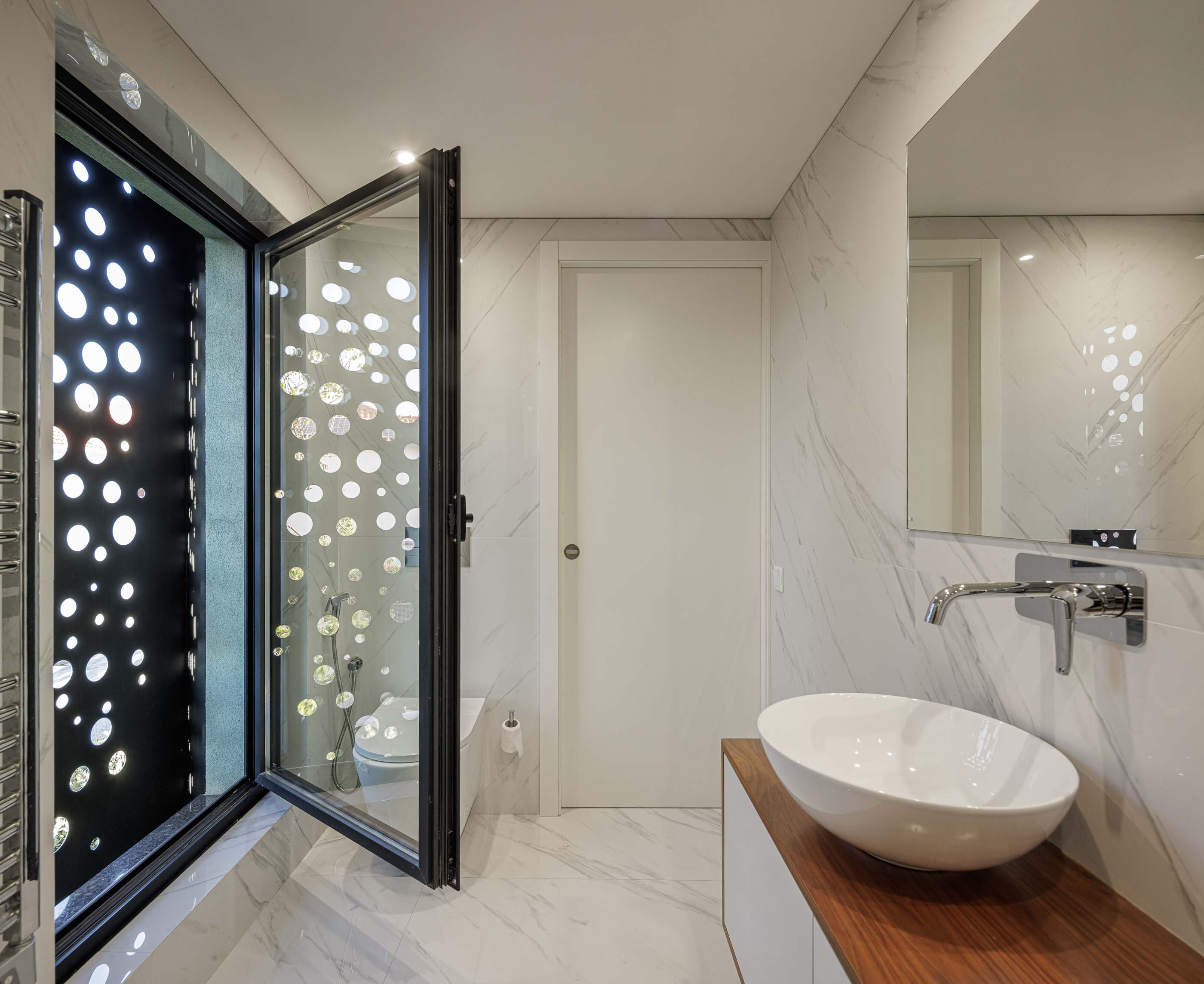 Exterior: Detalhe do anexo preto perfurado da casa, com iluminação interior visível. — Casa Pi arquitetura ArquitectosRT em Porto