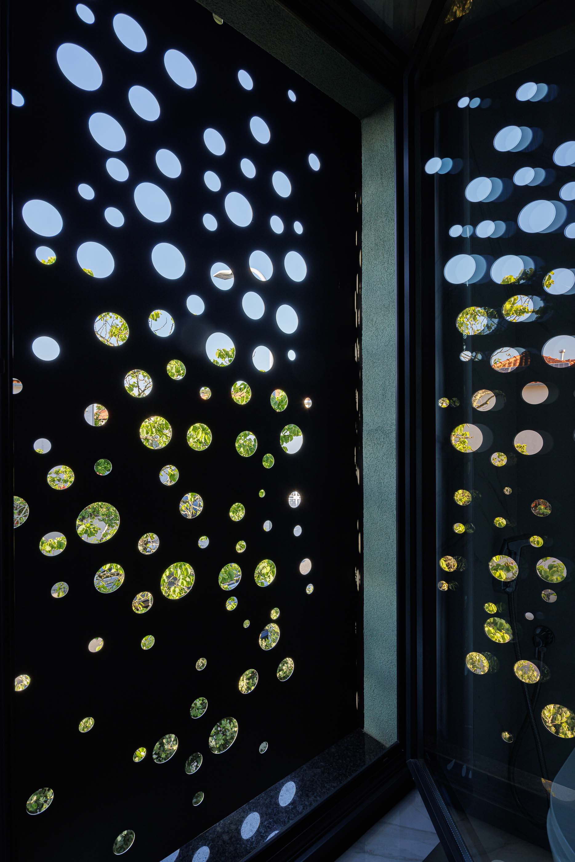 Exterior: Detalhe do anexo preto perfurado da casa, com telhado de telha e chaminé branca. — Casa Pi arquitetura ArquitectosRT em Porto