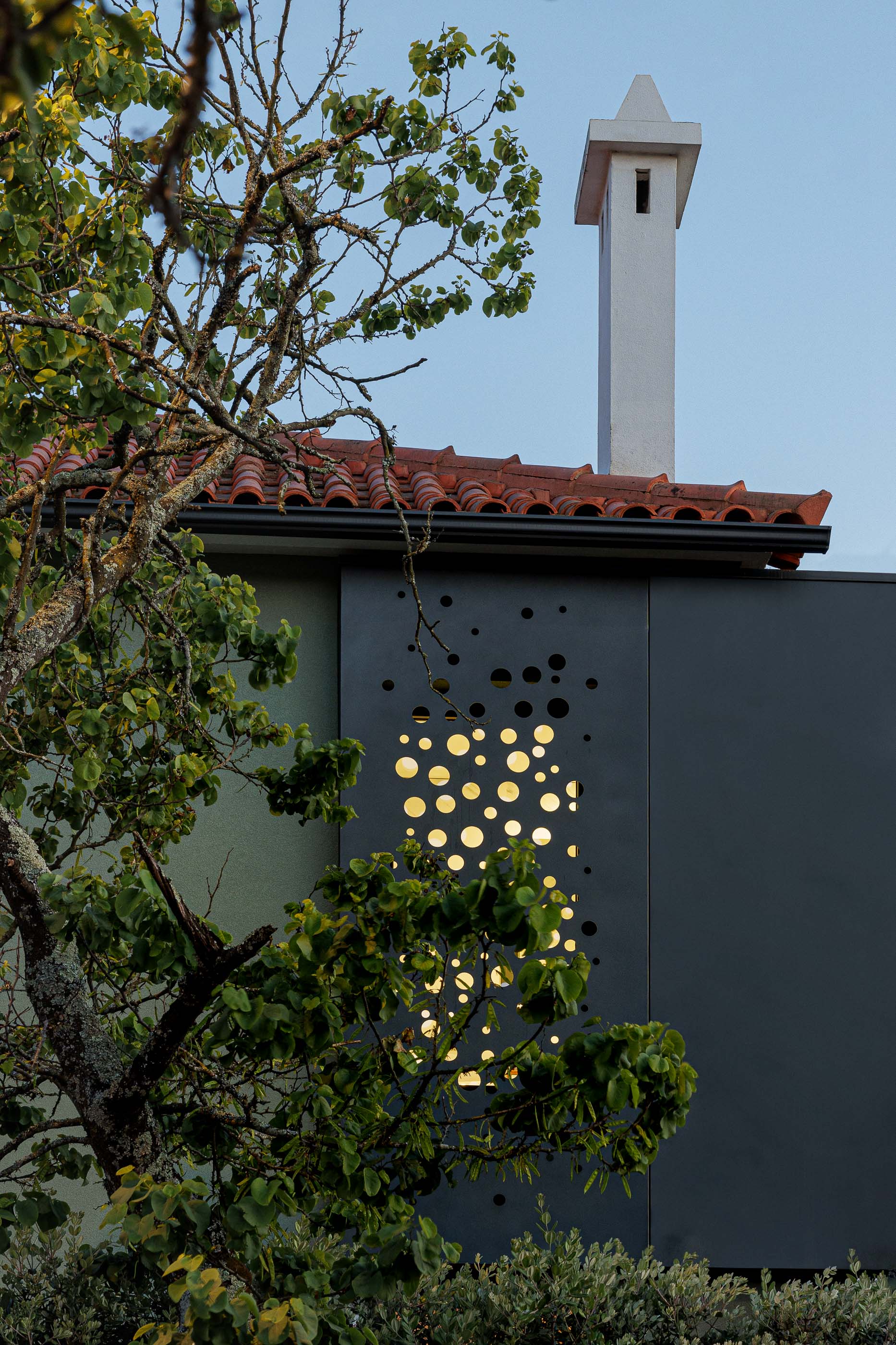 Exterior: Vista noturna da casa com anexo preto, marquise envidraçada e jardim. — Casa Pi arquitetura ArquitectosRT em Porto