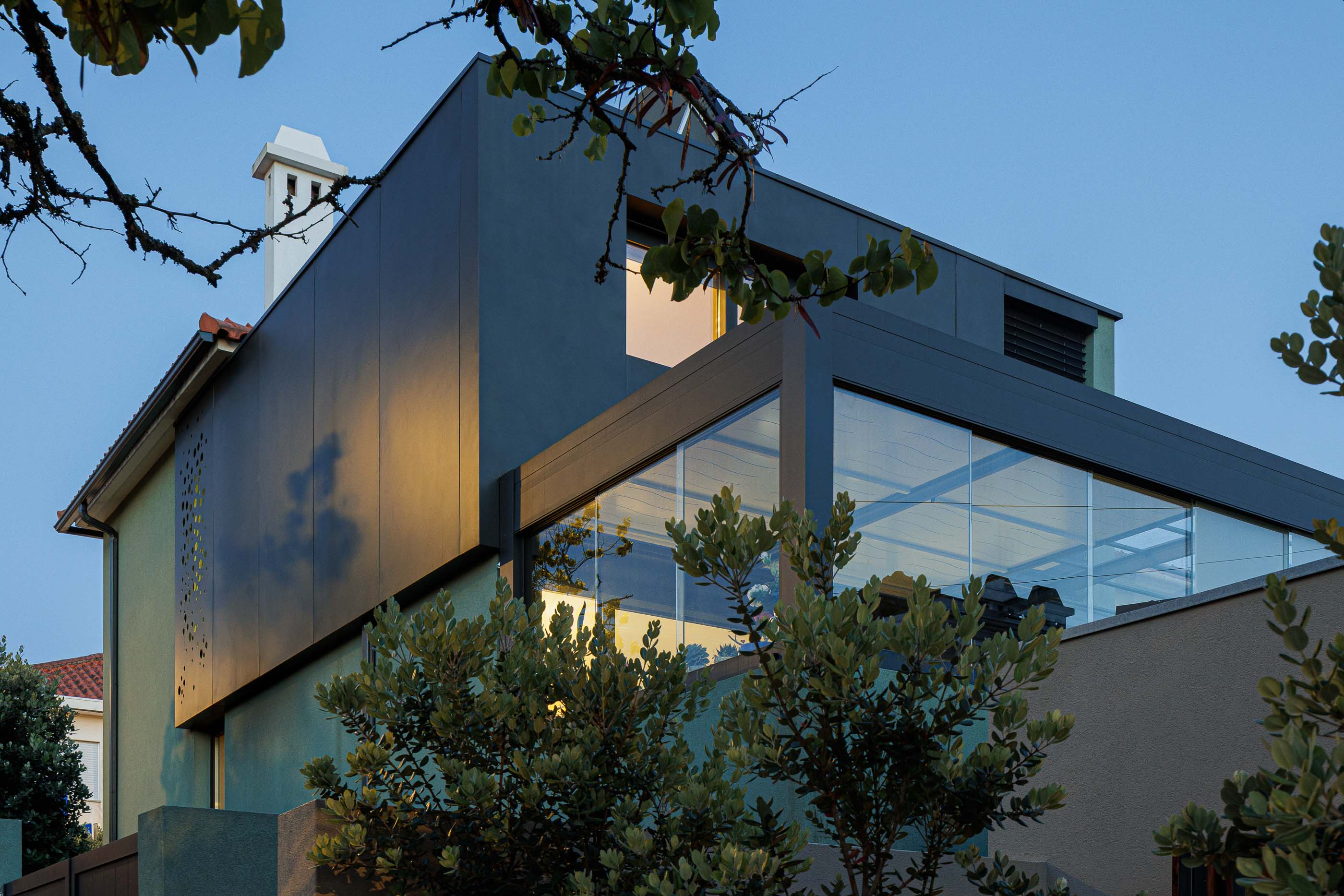 Exterior: Vista noturna da casa verde com anexo preto e jardim. — Casa Pi arquitetura ArquitectosRT em Porto