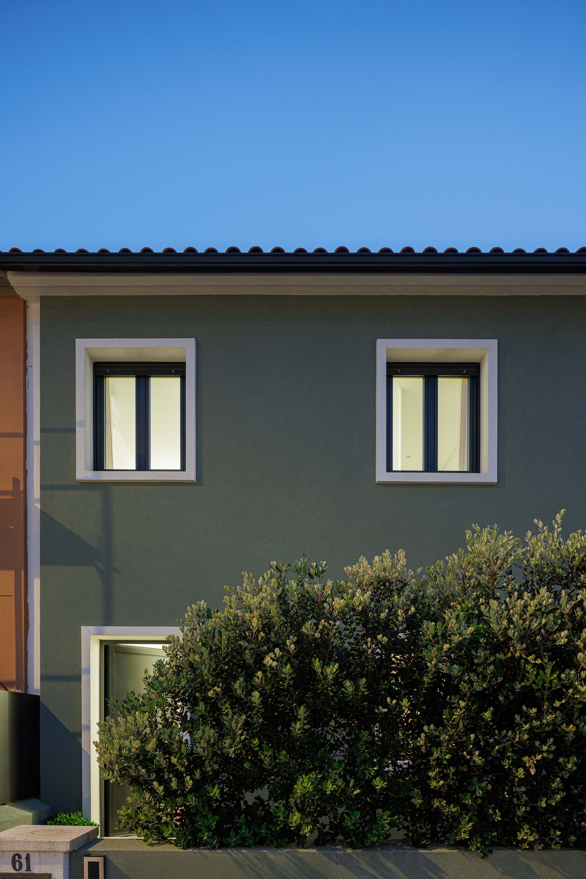 Exterior: Detalhe do anexo preto perfurado da casa, com janela iluminada. — Casa Pi arquitetura ArquitectosRT em Porto