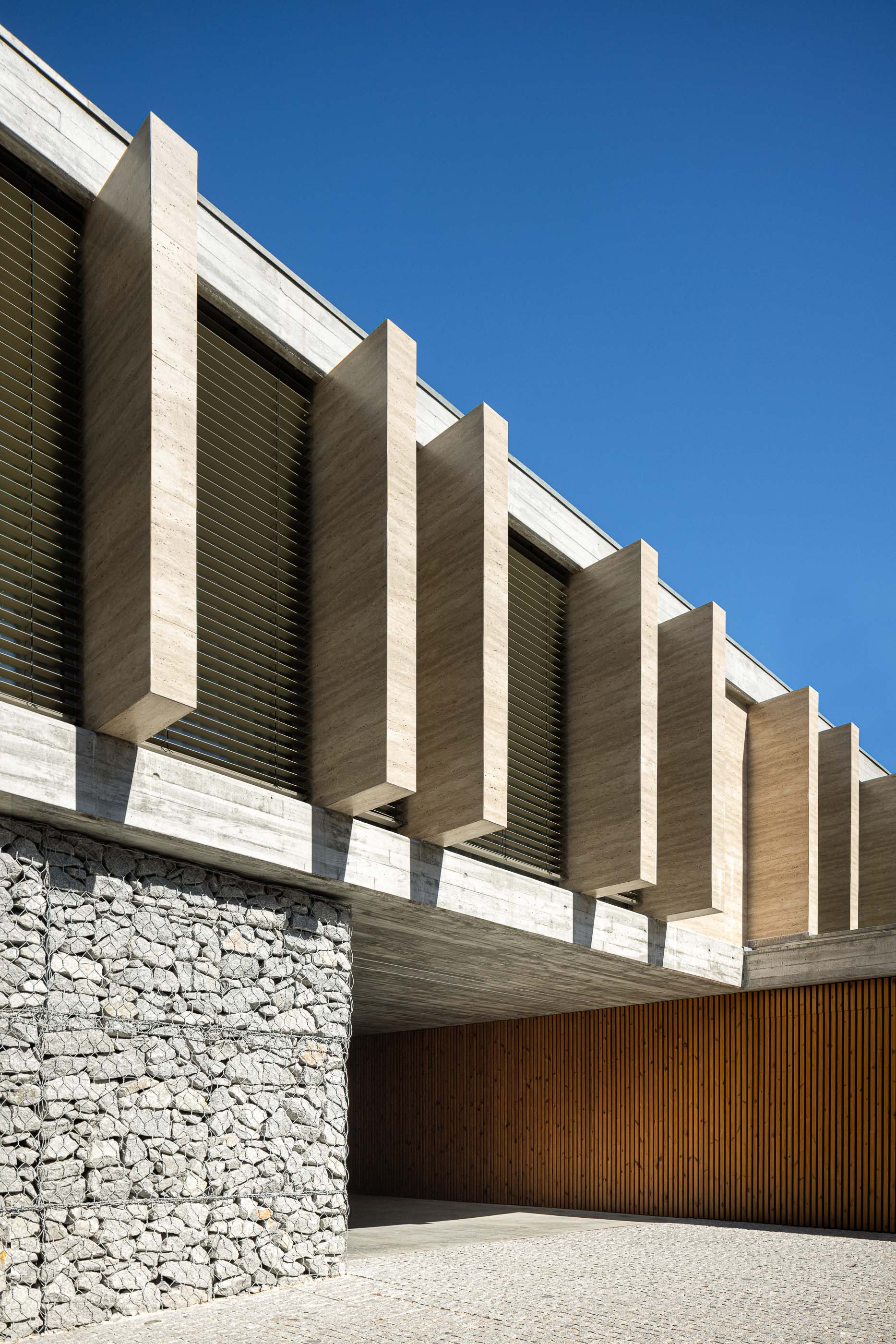 Fachada: Detalhe da fachada com elementos verticais em betão e revestimento em pedra. — Habitação CL arquitetura Artequitectos em Guimarães