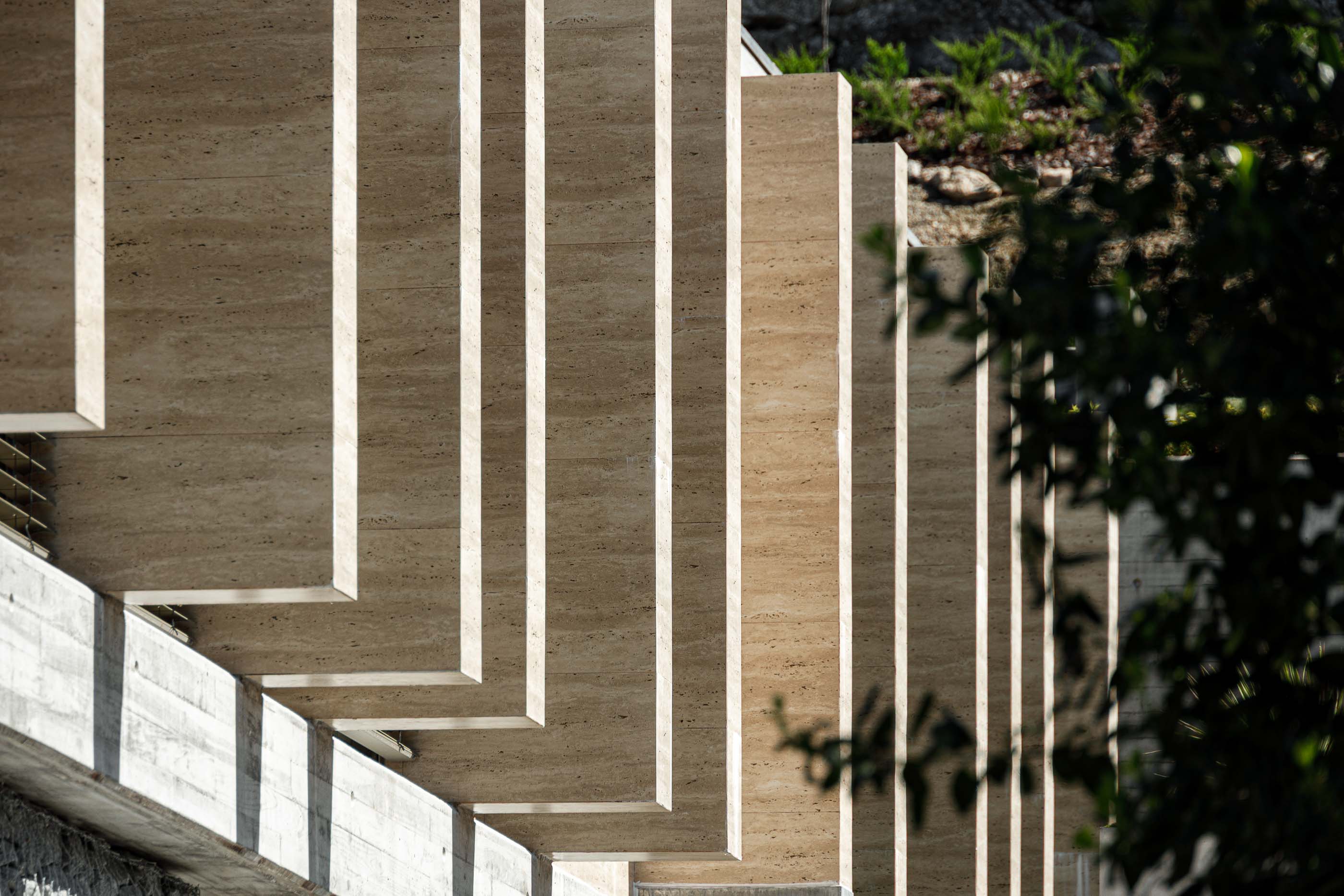Fachada: Elementos verticais em betão da fachada, com vegetação em segundo plano. — Habitação CL arquitetura Artequitectos em Guimarães
