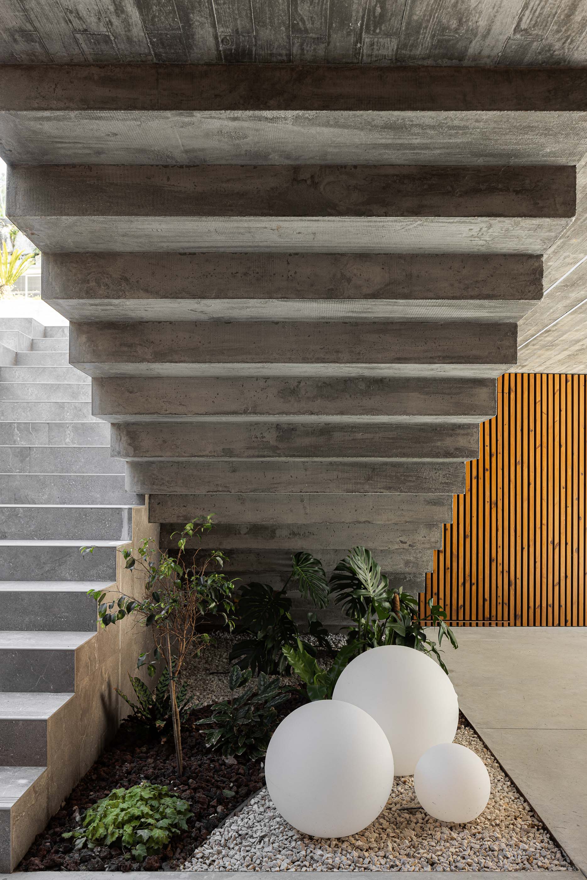 Escadas: Detalhe das escadas em betão, com jardim interior e revestimento em madeira. — Habitação CL arquitetura Artequitectos em Guimarães