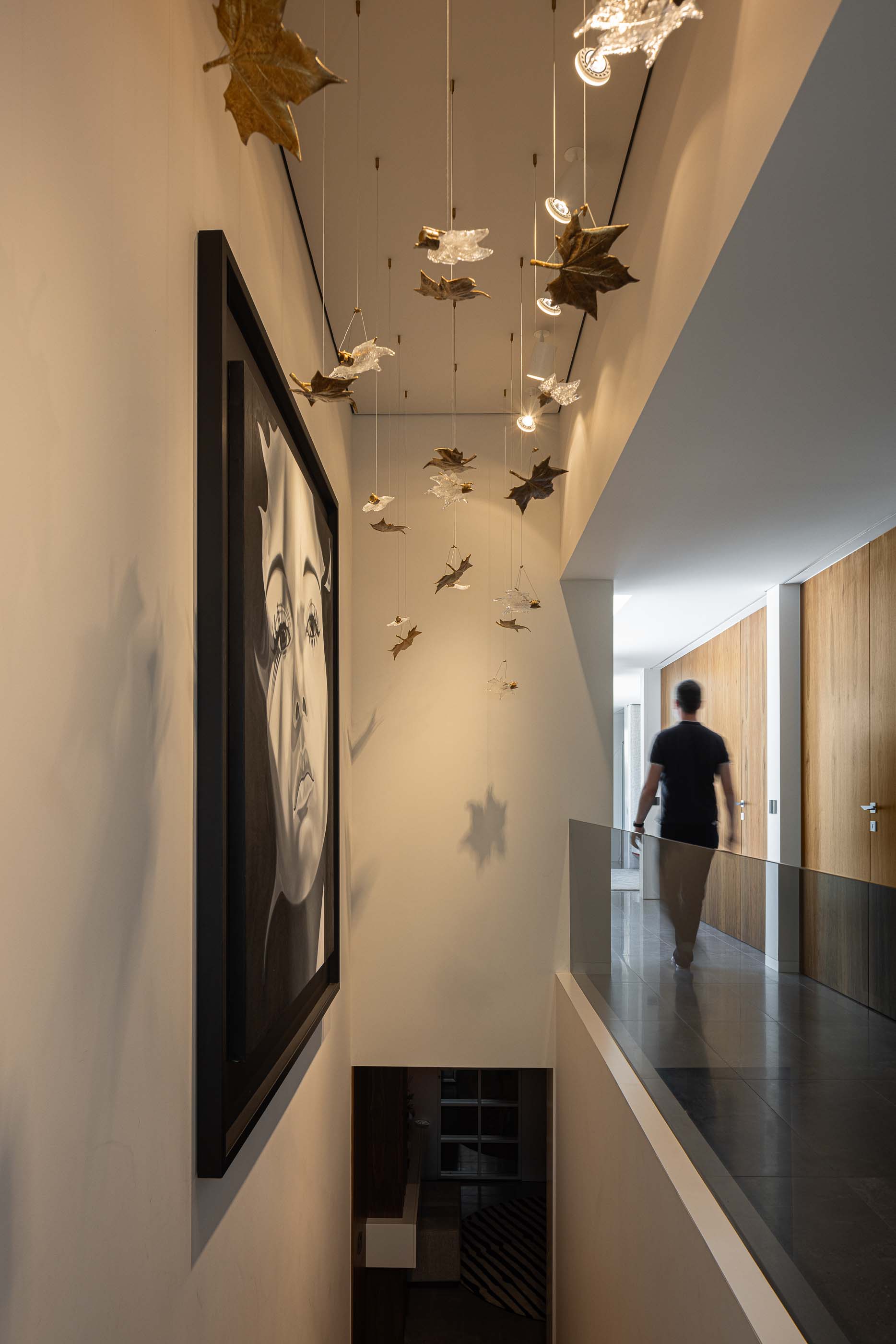Corredor: Corredor no piso superior com candeeiro decorativo, quadro e guarda em vidro. — Habitação CL arquitetura Artequitectos em Guimarães