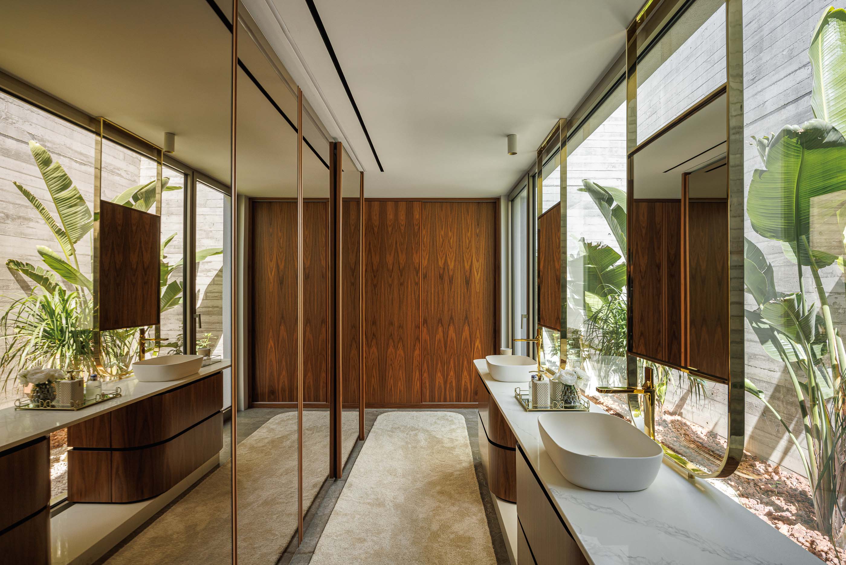 Casa de banho: Casa de banho com lavatórios duplos, espelhos e armários em madeira, com vista para o jardim. — Habitação CL arquitetura Artequitectos em Guimarães