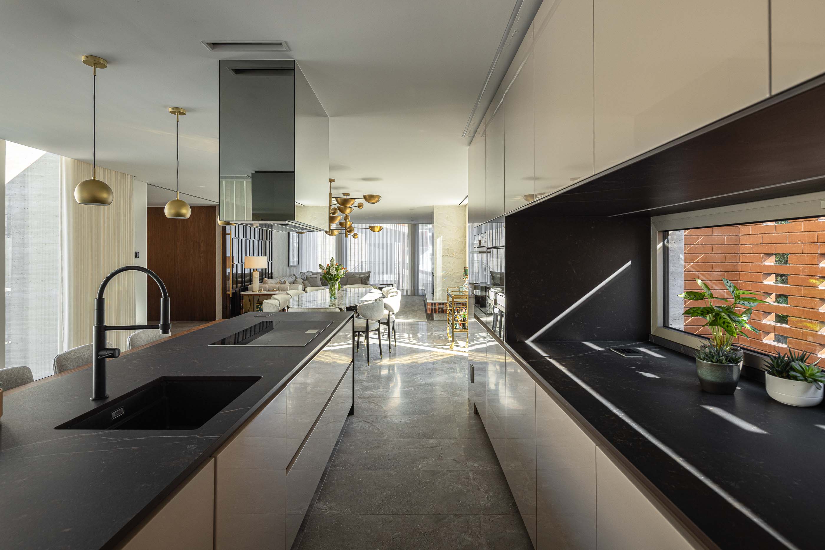 Cozinha: Cozinha moderna com bancada em pedra escura e vista para a sala de estar. — Habitação CL arquitetura Artequitectos em Guimarães