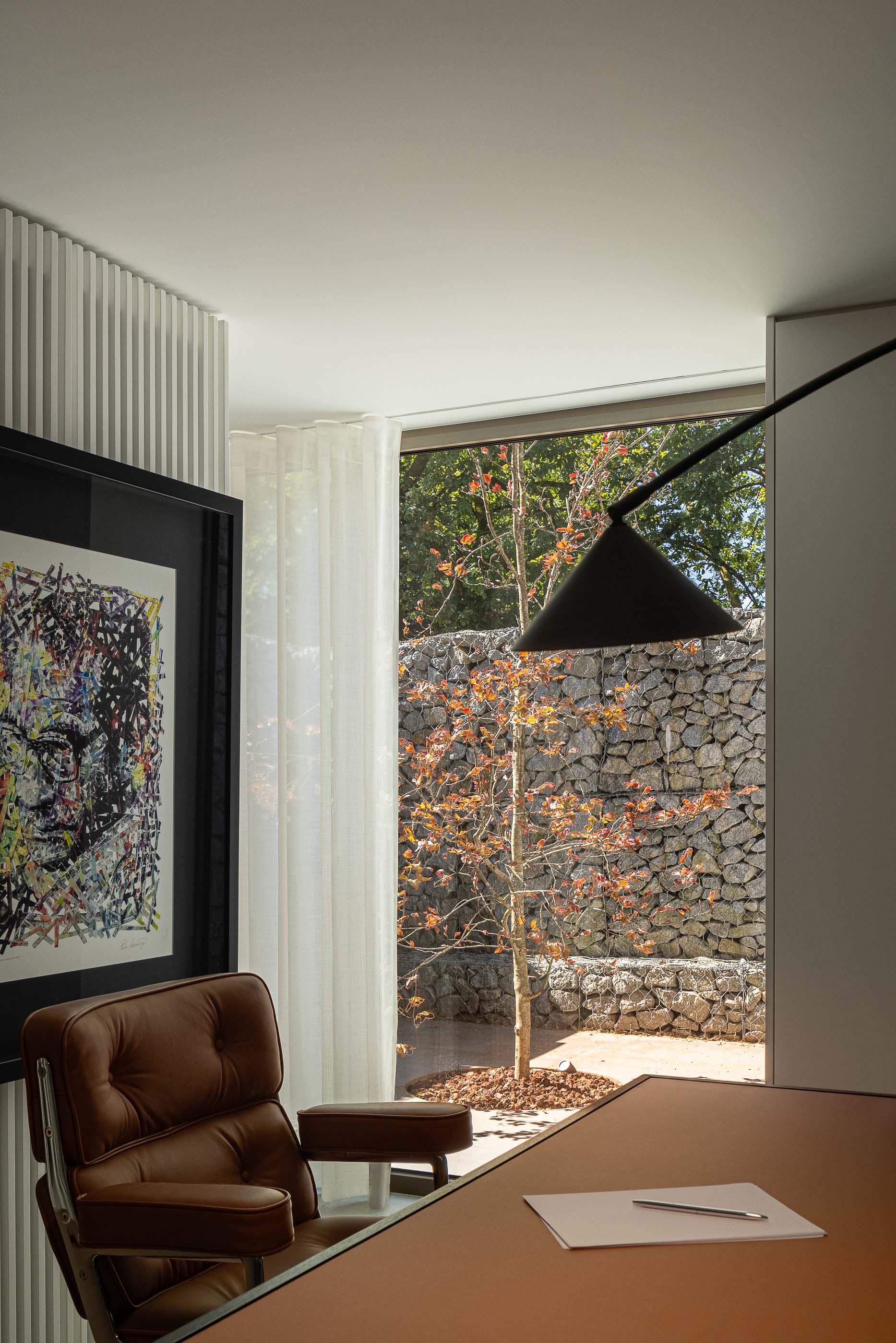 Escritório: Escritório com secretária em madeira, cadeira em pele e vista para o jardim. — Habitação CL arquitetura Artequitectos em Guimarães