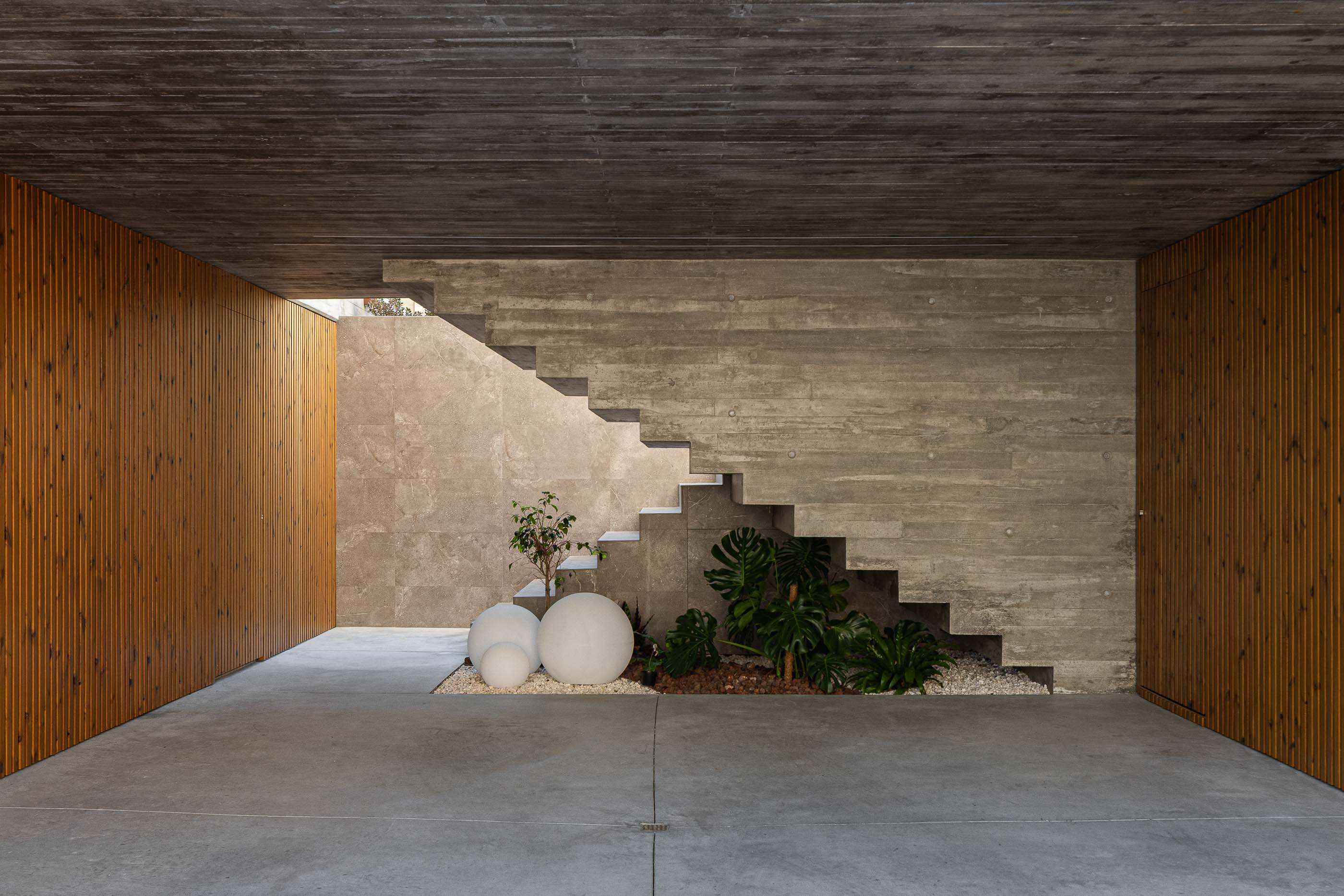 Garagem: Garagem com escadas de acesso ao piso superior, jardim interior e revestimento em madeira. — Habitação CL arquitetura Artequitectos em Guimarães