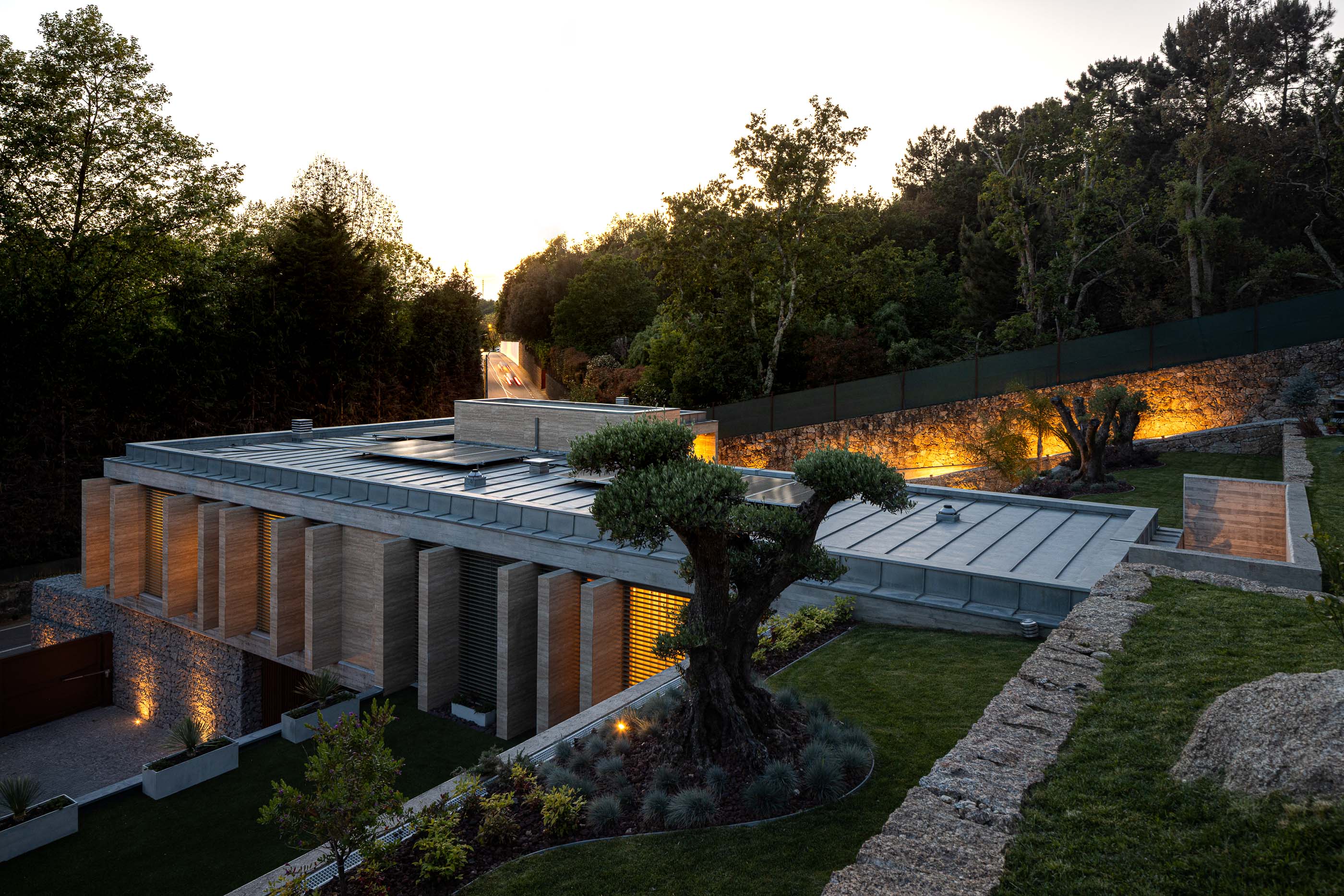 Exterior: Vista aérea noturna da casa com jardim, piscina e iluminação. — Habitação CL arquitetura Artequitectos em Guimarães