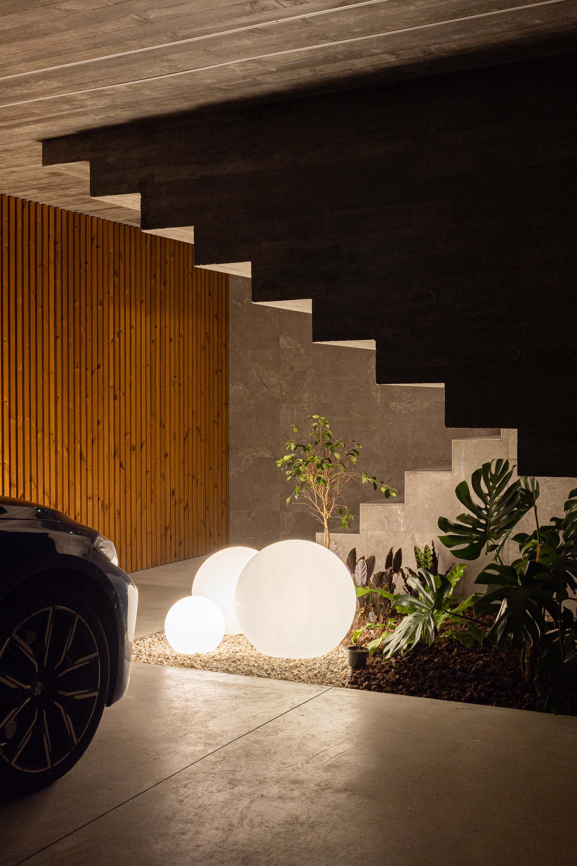 Garagem: Garagem com carro estacionado, escadas, jardim interior e iluminação. — Habitação CL arquitetura Artequitectos em Guimarães