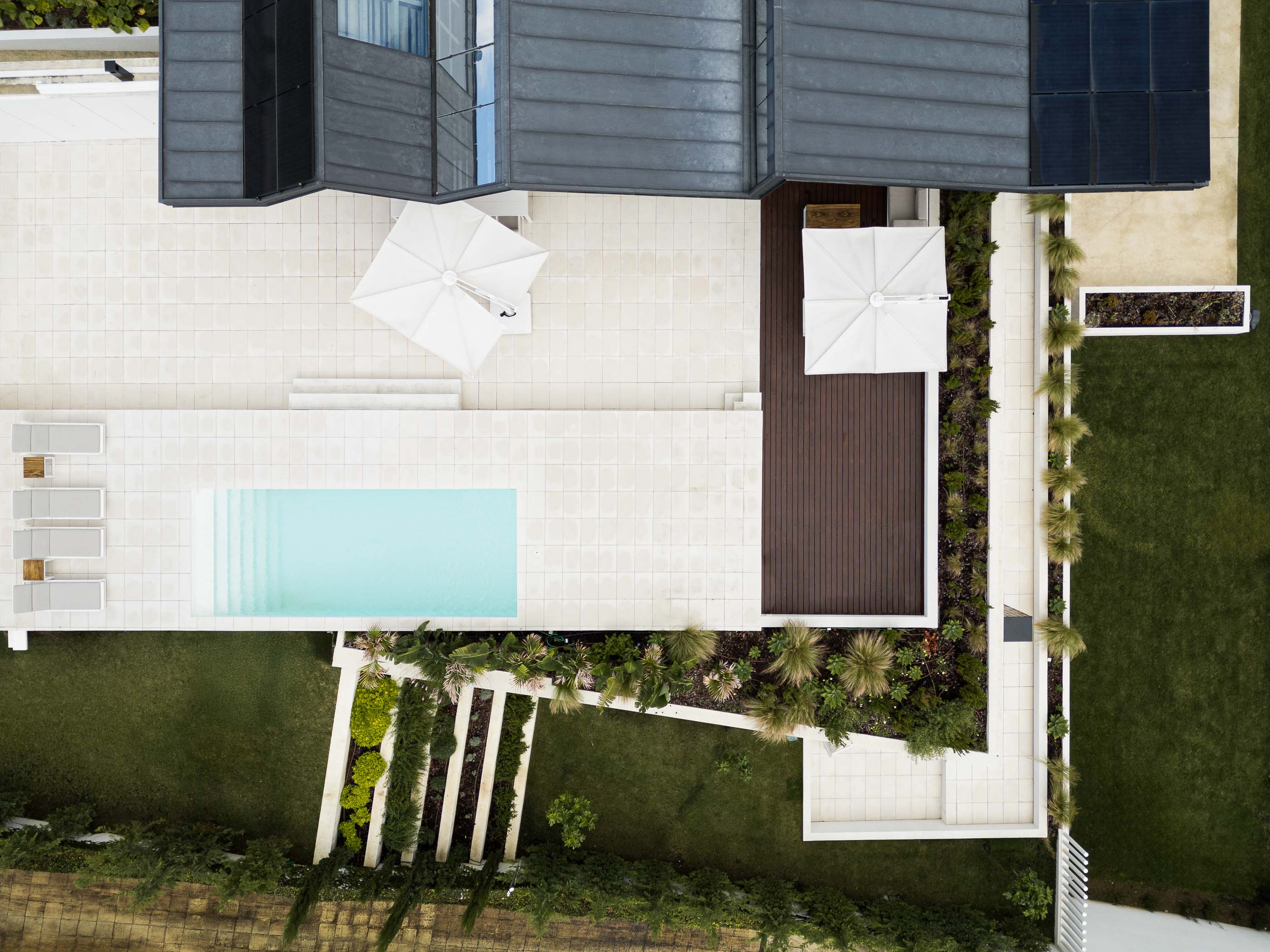 Exterior: Vista aérea da casa com piscina, terraço em pedra, deck em madeira e jardim com vegetação organizada. — Casa dos Alcoutins arquitetura Paulo Martins Arquitectura e Design em Lisboa