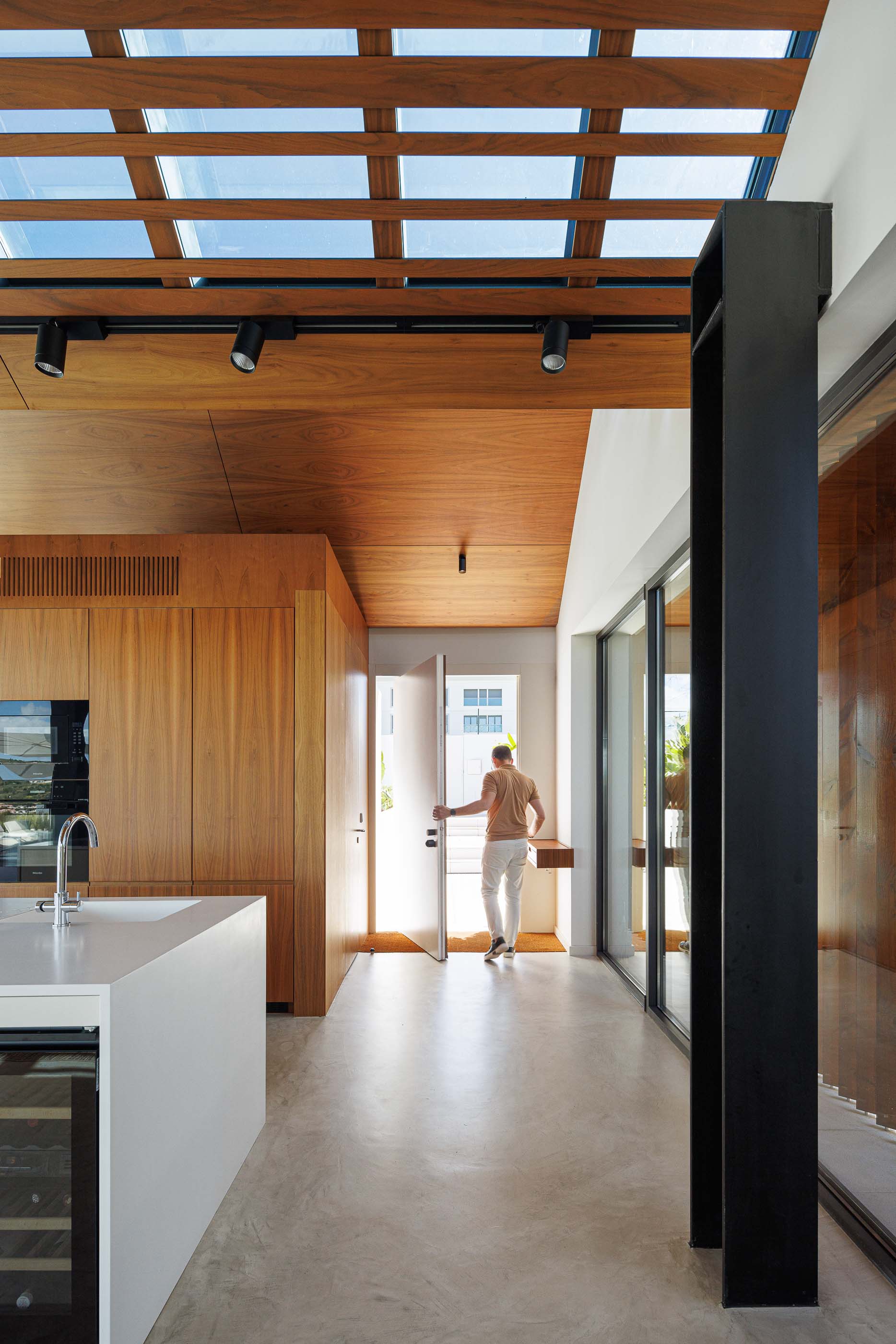 Cozinha: Interior com teto em madeira, iluminação embutida, bancada branca e porta de acesso ao exterior. — Casa dos Alcoutins arquitetura Paulo Martins Arquitectura e Design em Lisboa